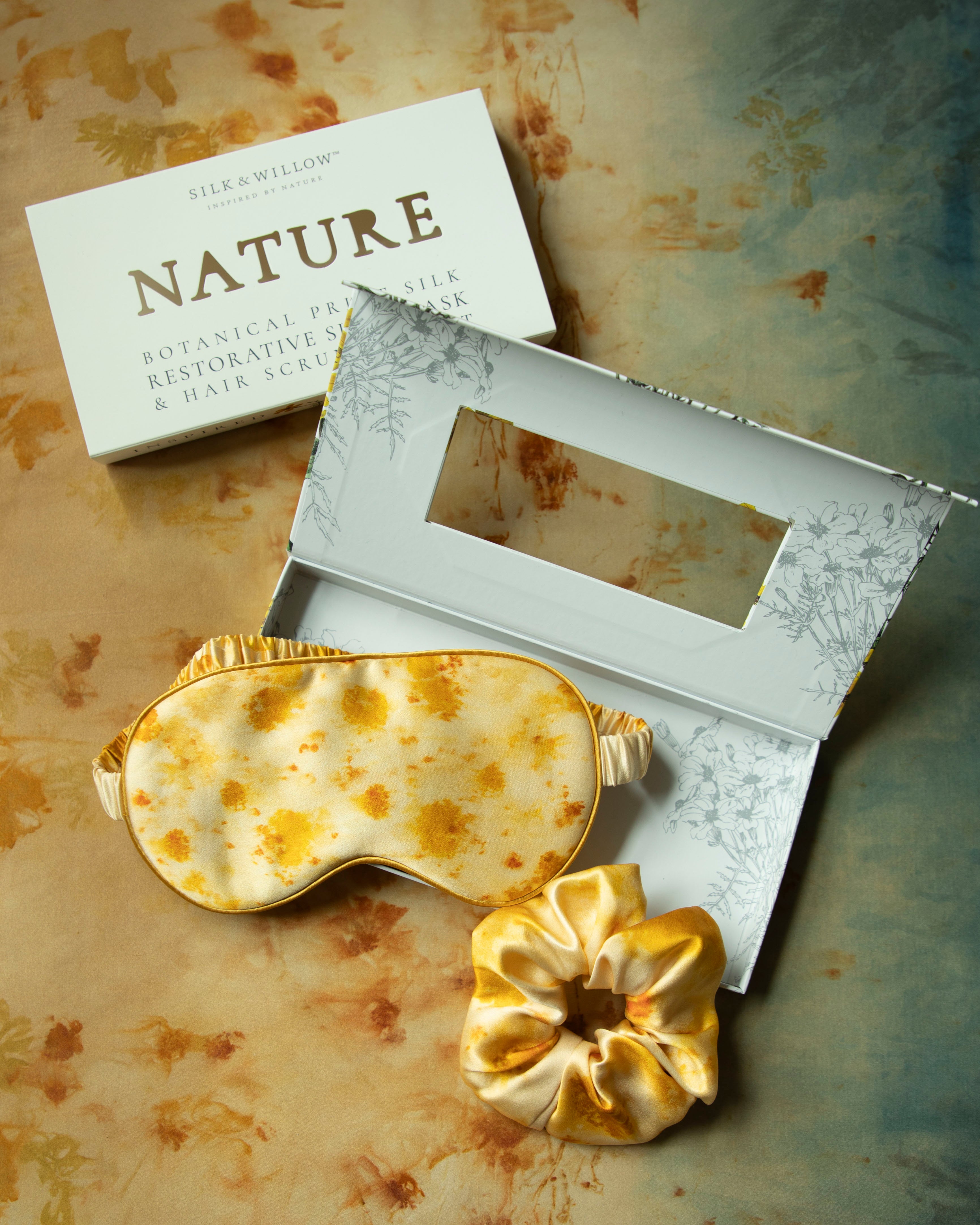 Gold-patterned eye mask and flower on a textured surface with 'NATURE' branding.