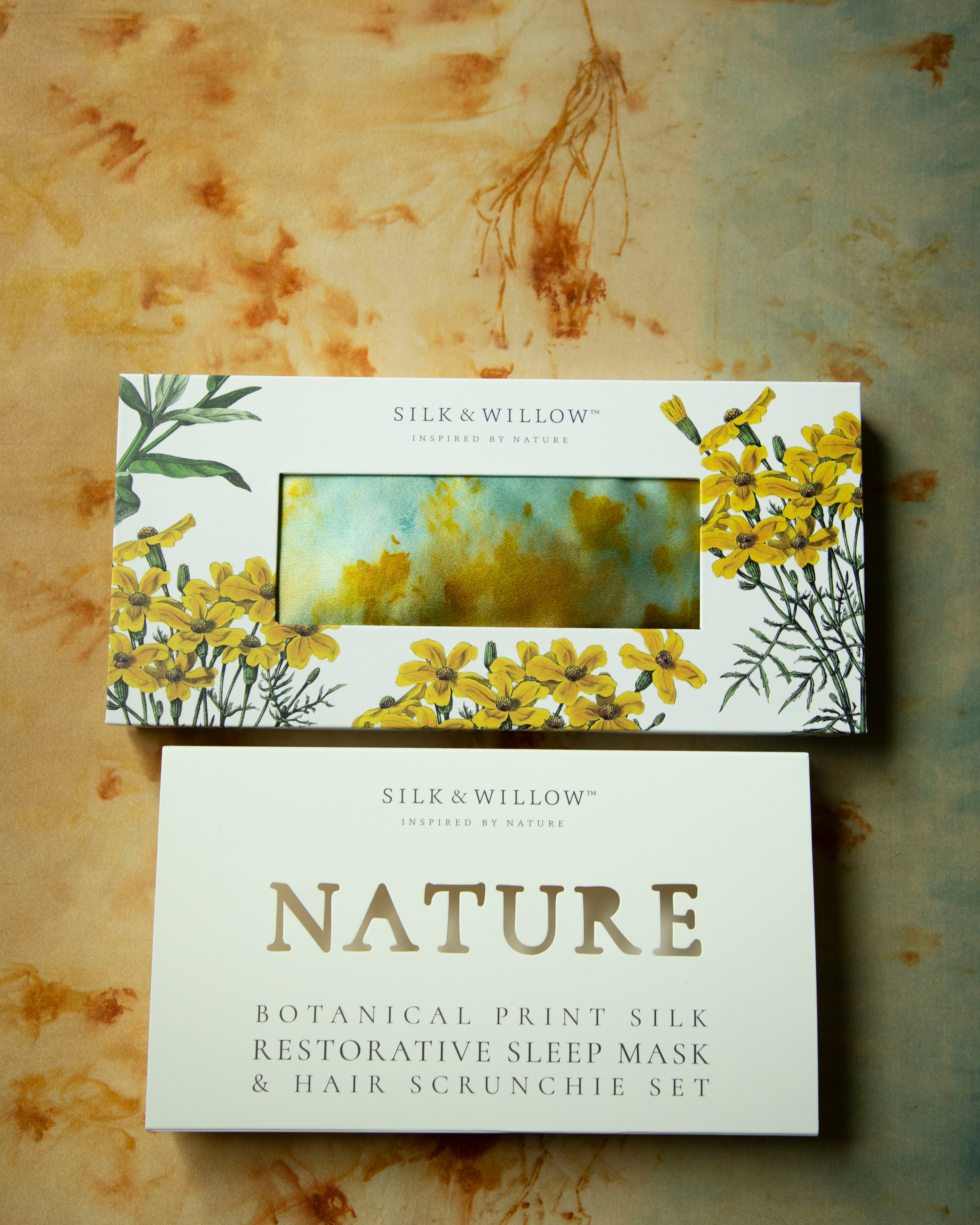 Silk and Willow botanical print silk restorative sleep mask and hair scrunchie set on a textured background