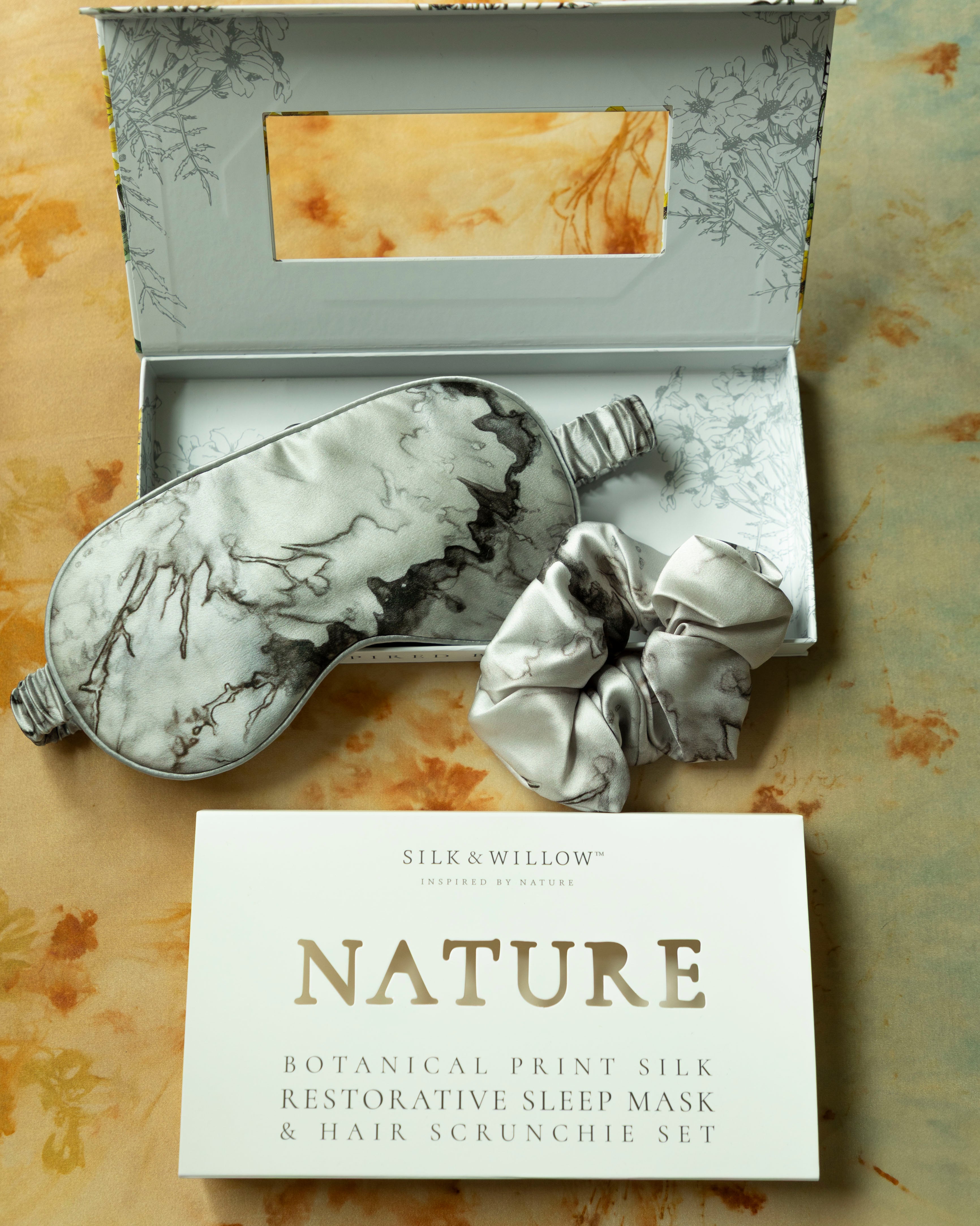 Silk sleep mask and hair scrunchie set with 'NATURE' card on a textured background