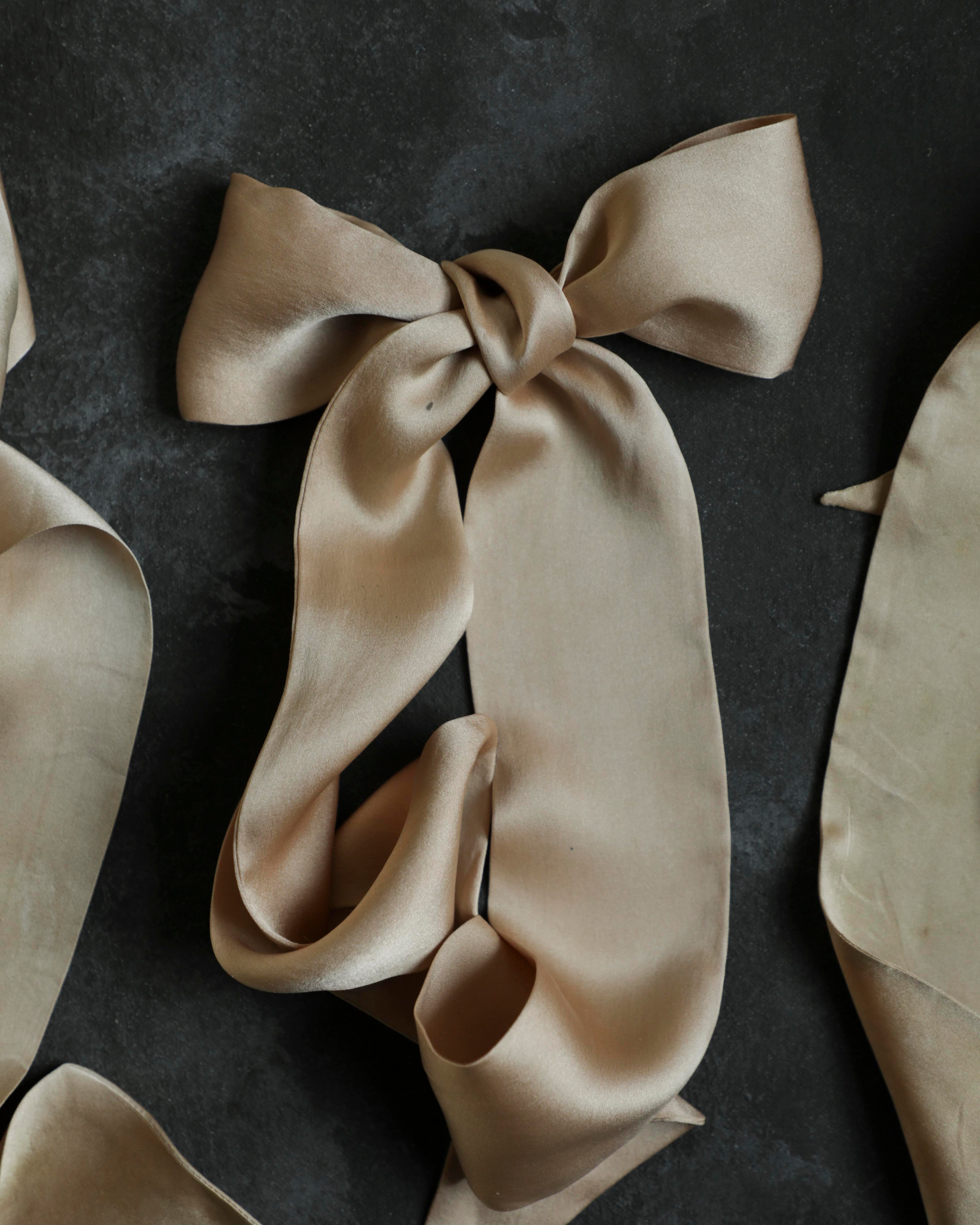 Beige silk scarf tied in a bow on a dark background