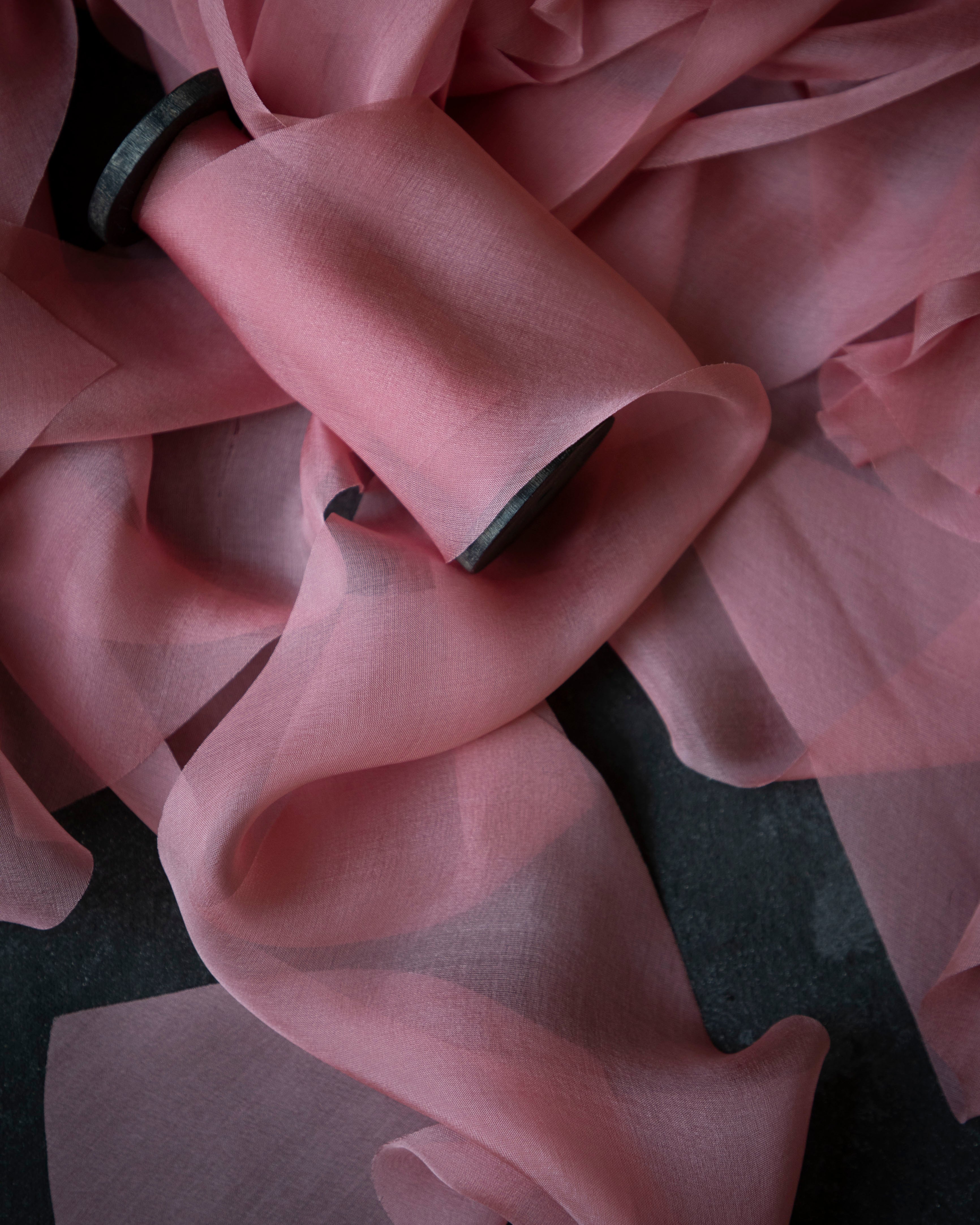 Close-up of a pink silk ribbon with a dark background