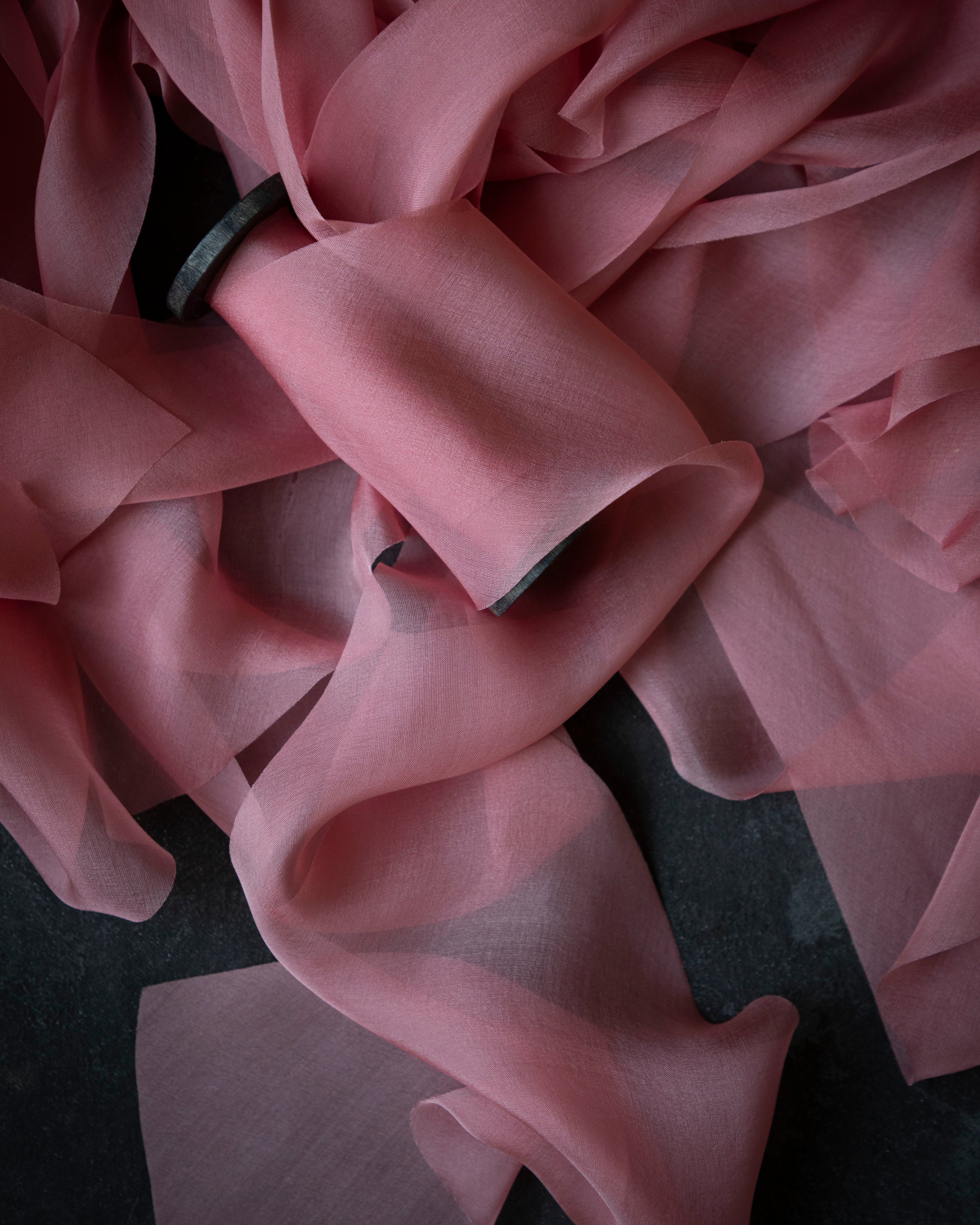 Close-up of pink ribbon with ruffled texture on a dark background