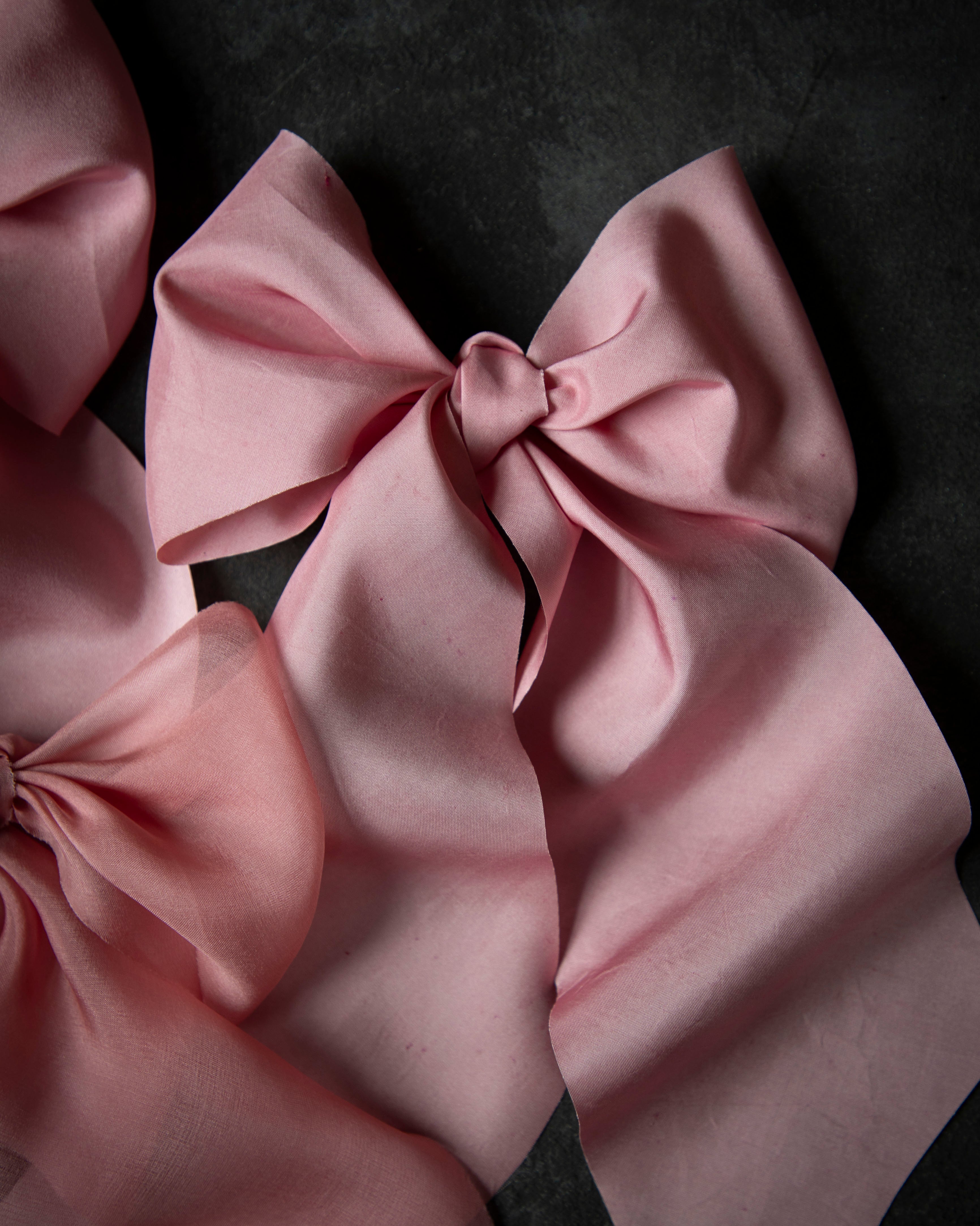 Pink satin hair bows on a dark background