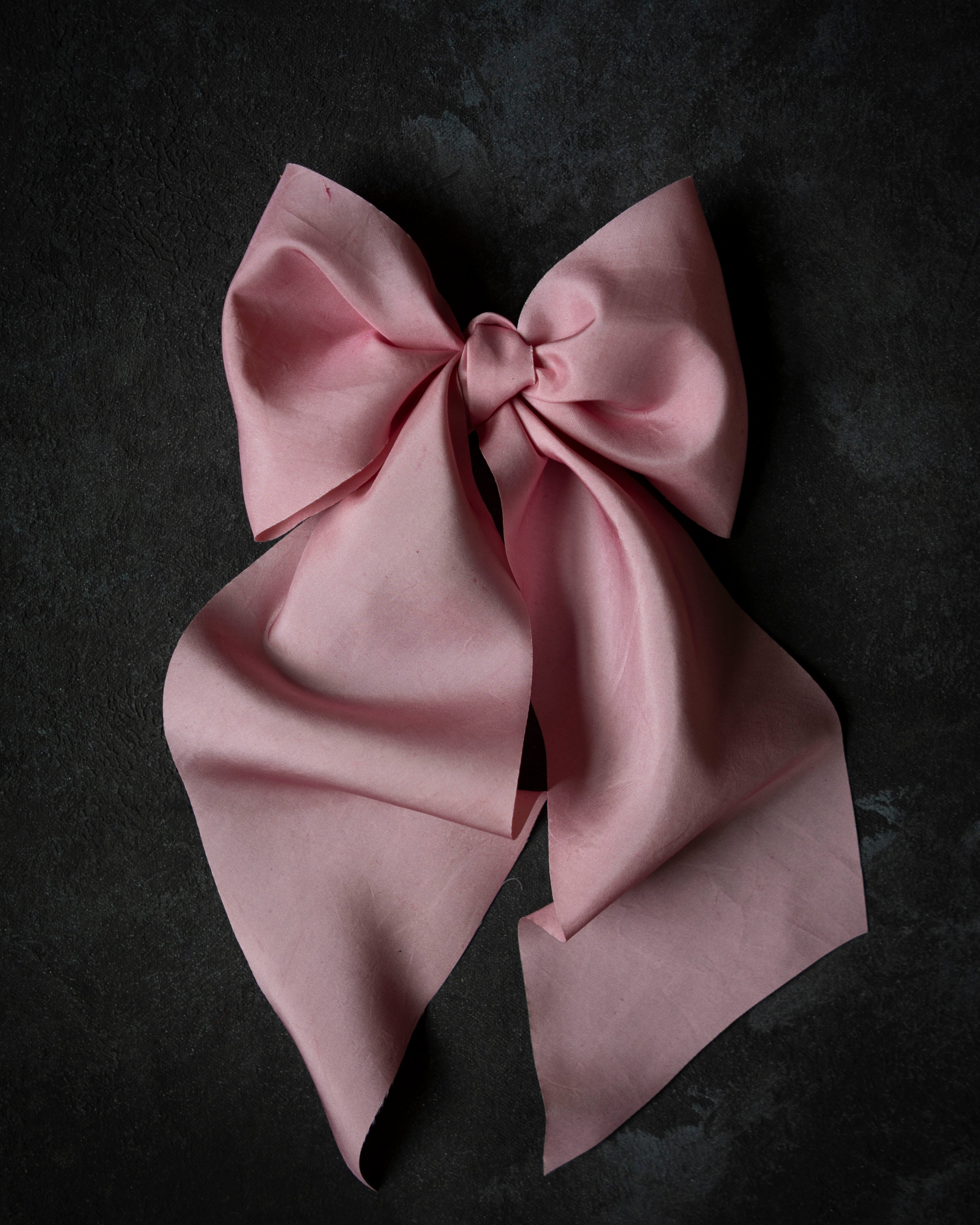 Pink satin bow on a dark background