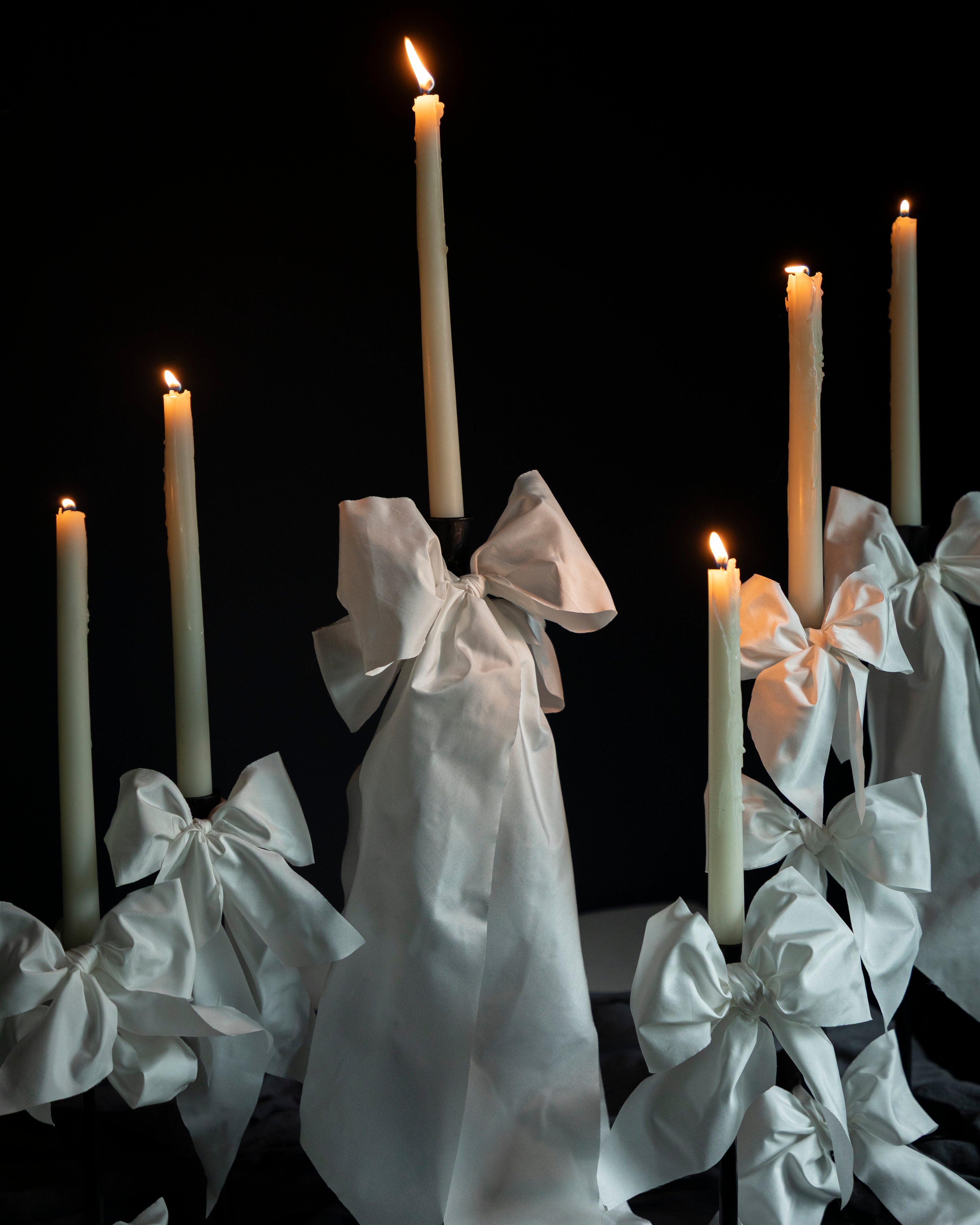 Candles with white ribbons against a black background