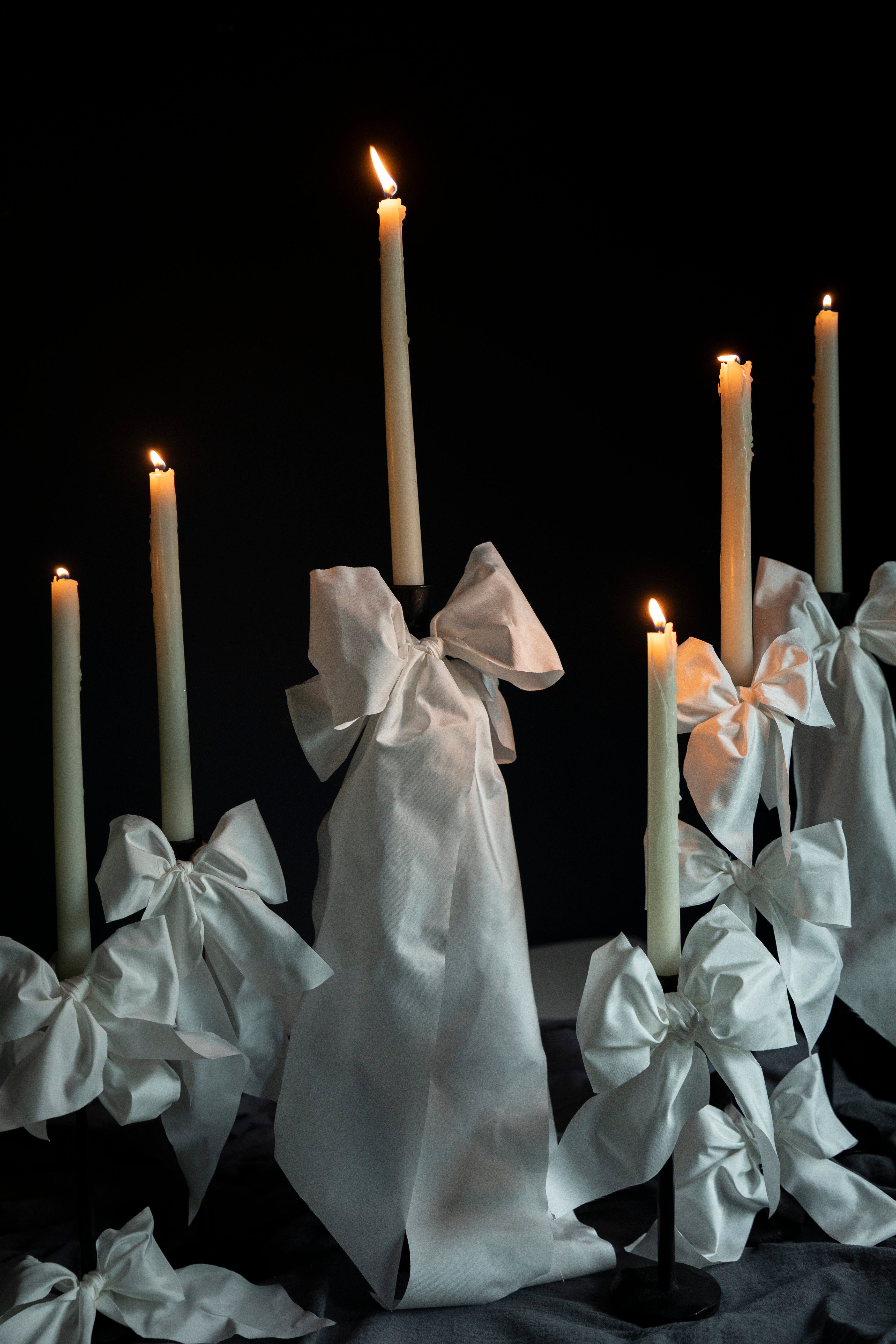 Candles with white ribbons against a black background