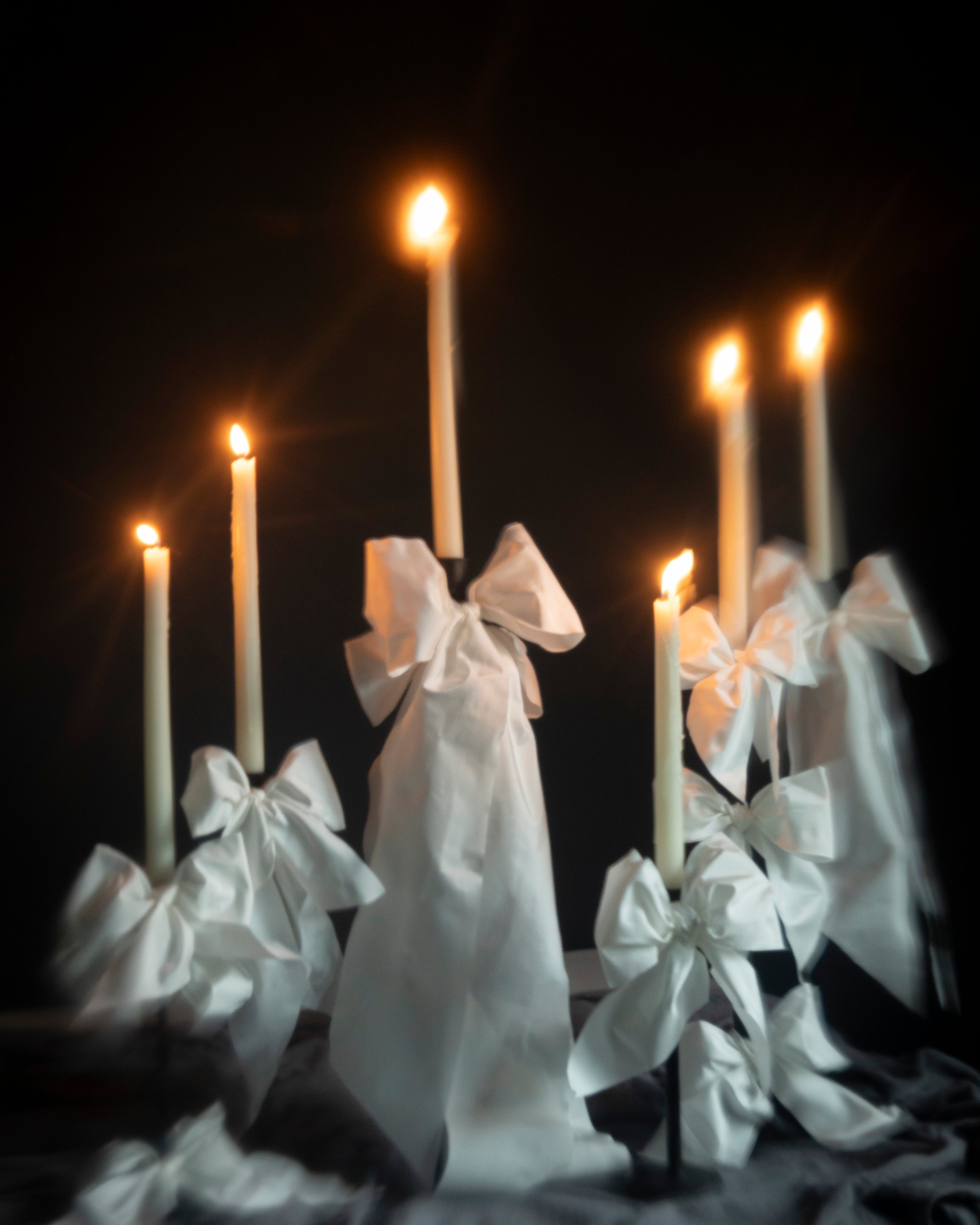 Candles wrapped with white ribbons on a dark background