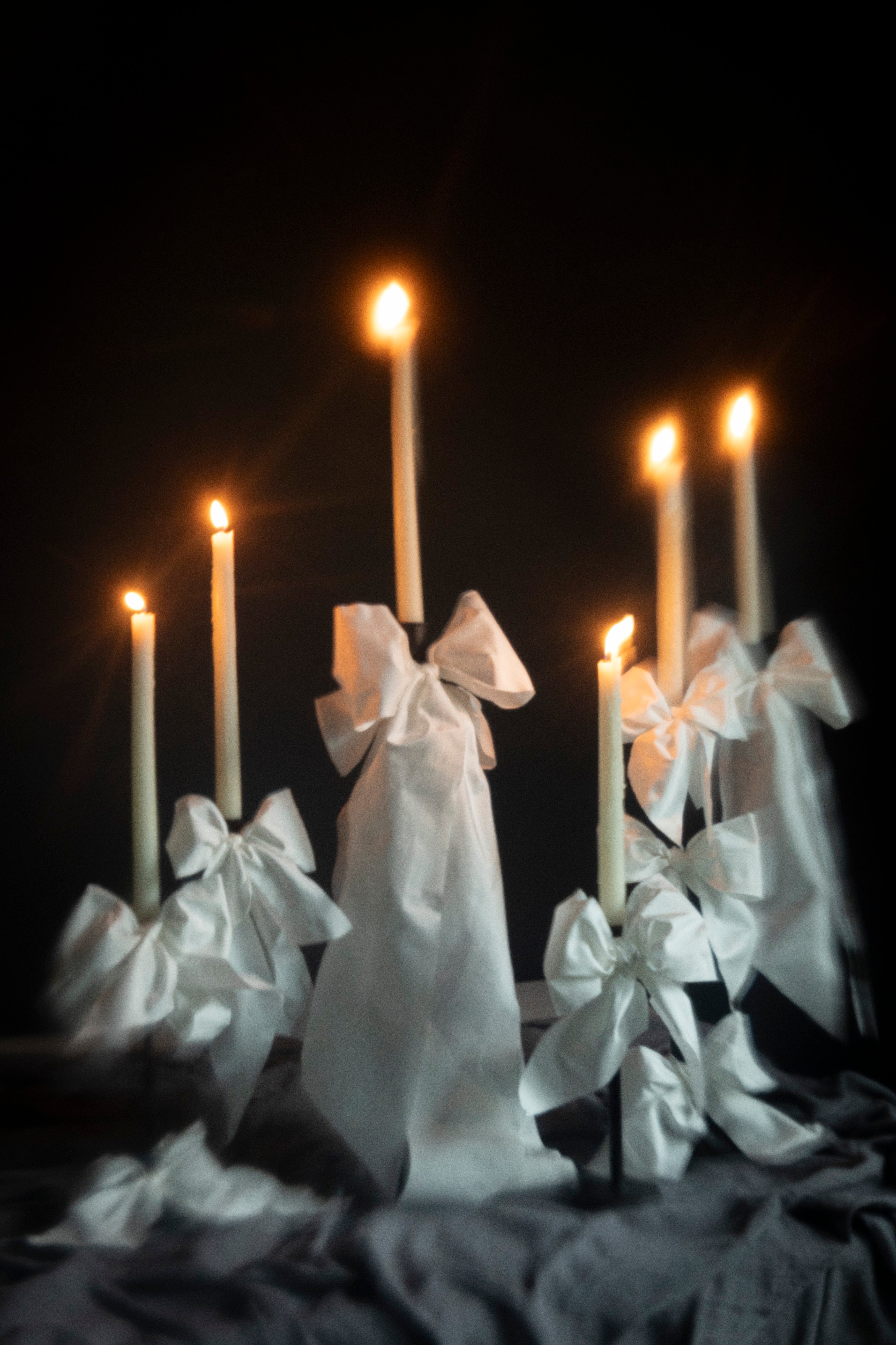 Candles wrapped with white ribbons on a dark background