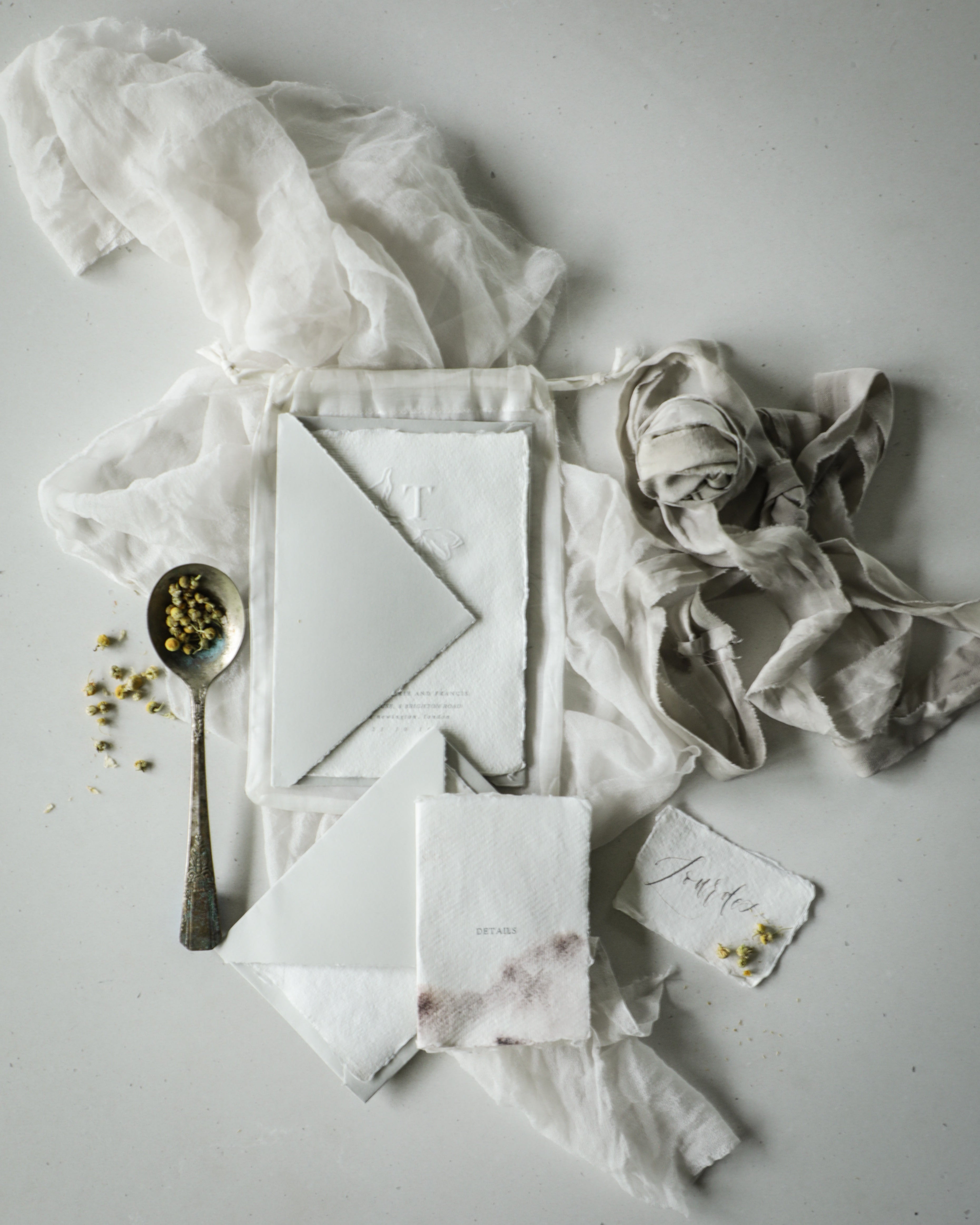 flat lay styling of wedding invitation suite with silk and willow sheer silk, handmade deckled edge paper and arpa envelopes