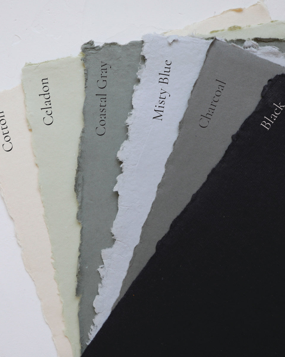 A selection of handmade papers with deckled edges in various shades including white, beige, gray, blue, and black, labeled with their respective color names.