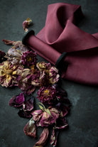 red silk ribbon on black textured surface next to dried rose petals