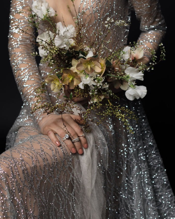 bride with metallic gown holding a bridal bouquet draped with silk ribbon