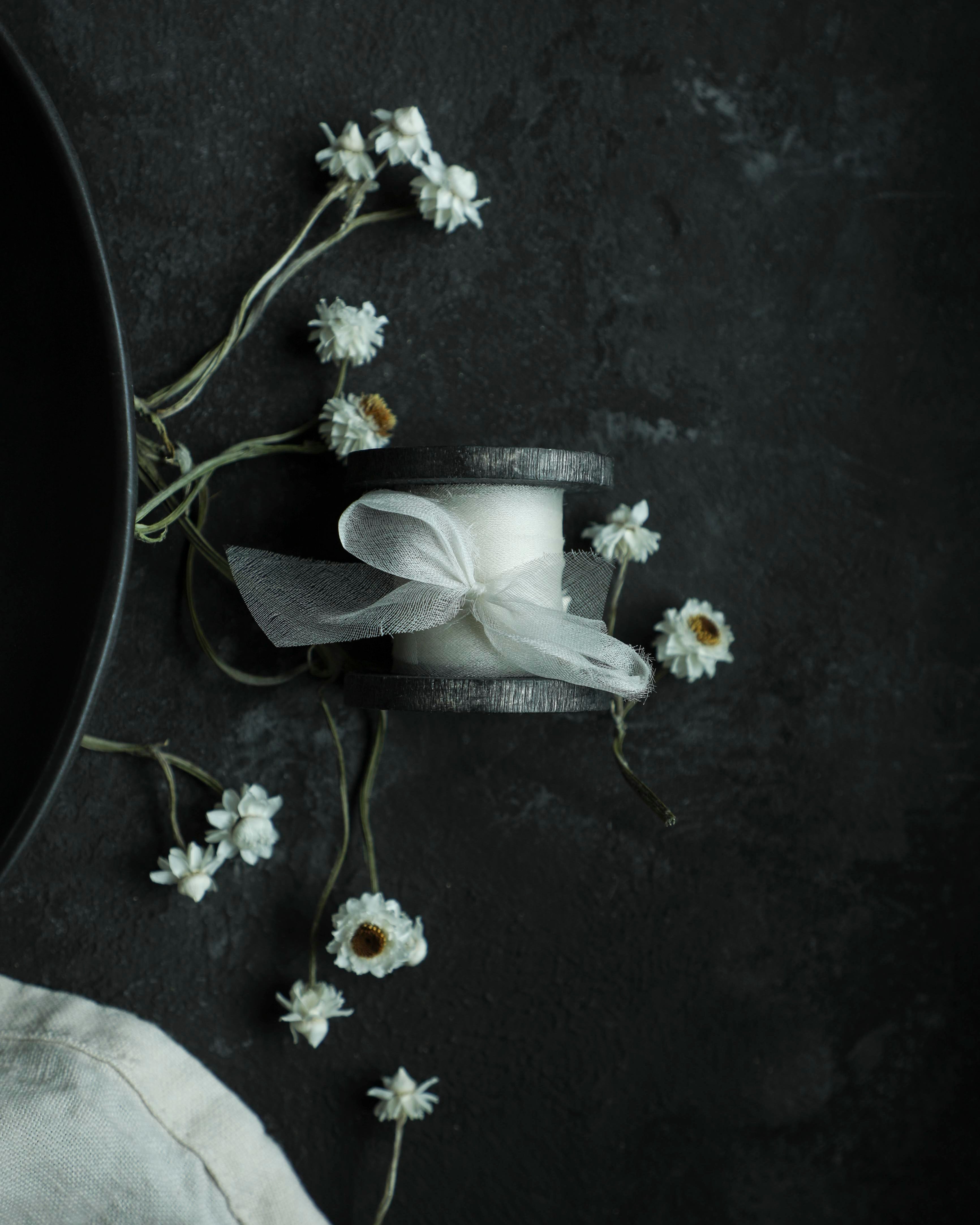 spool of ribbon on spool with dried flowers on a dark surface