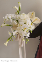 Bouquet of white flowers with a beige ribbon held by a person against a neutral background