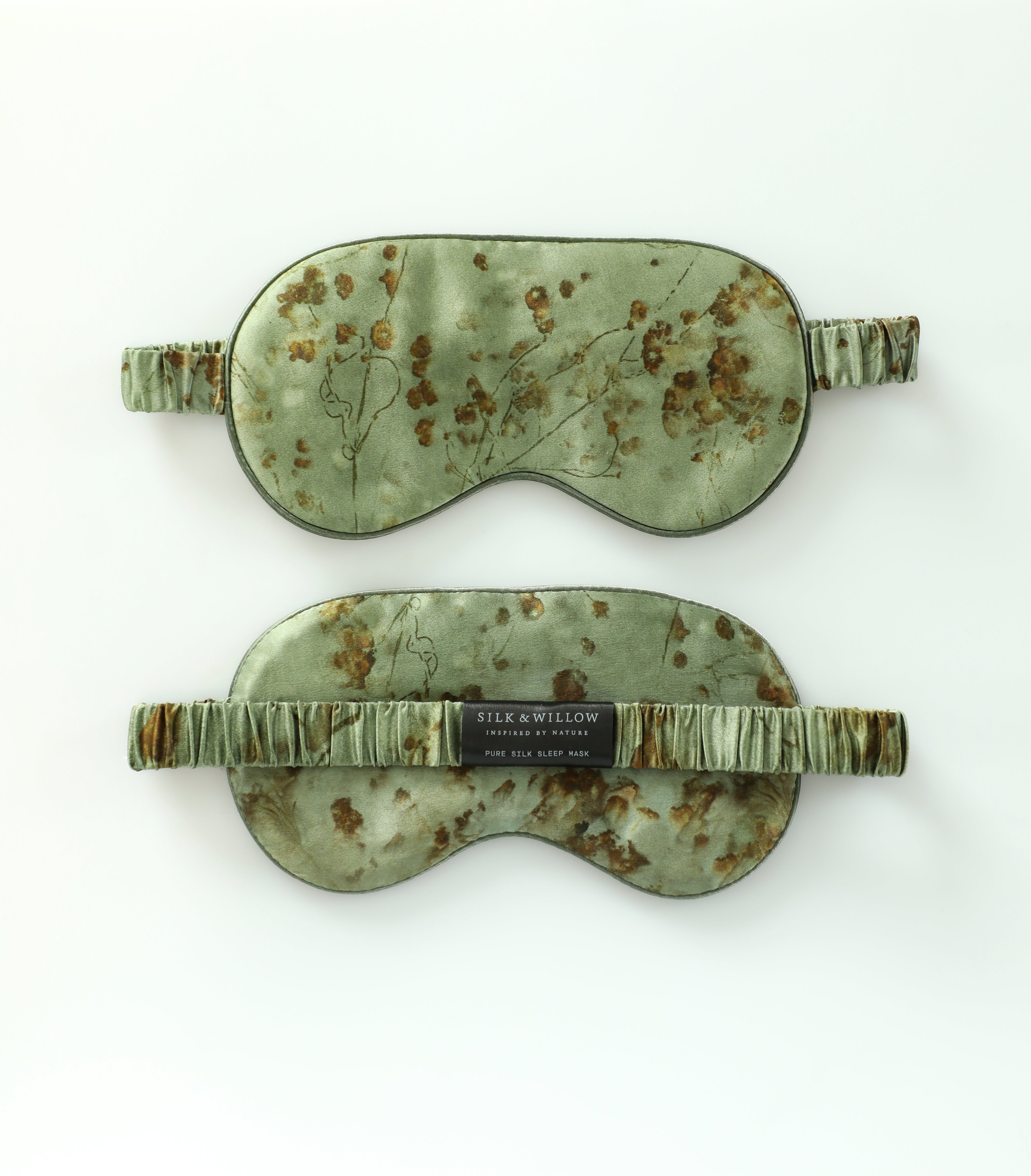 Two green sleep masks with floral patterns on a white background
