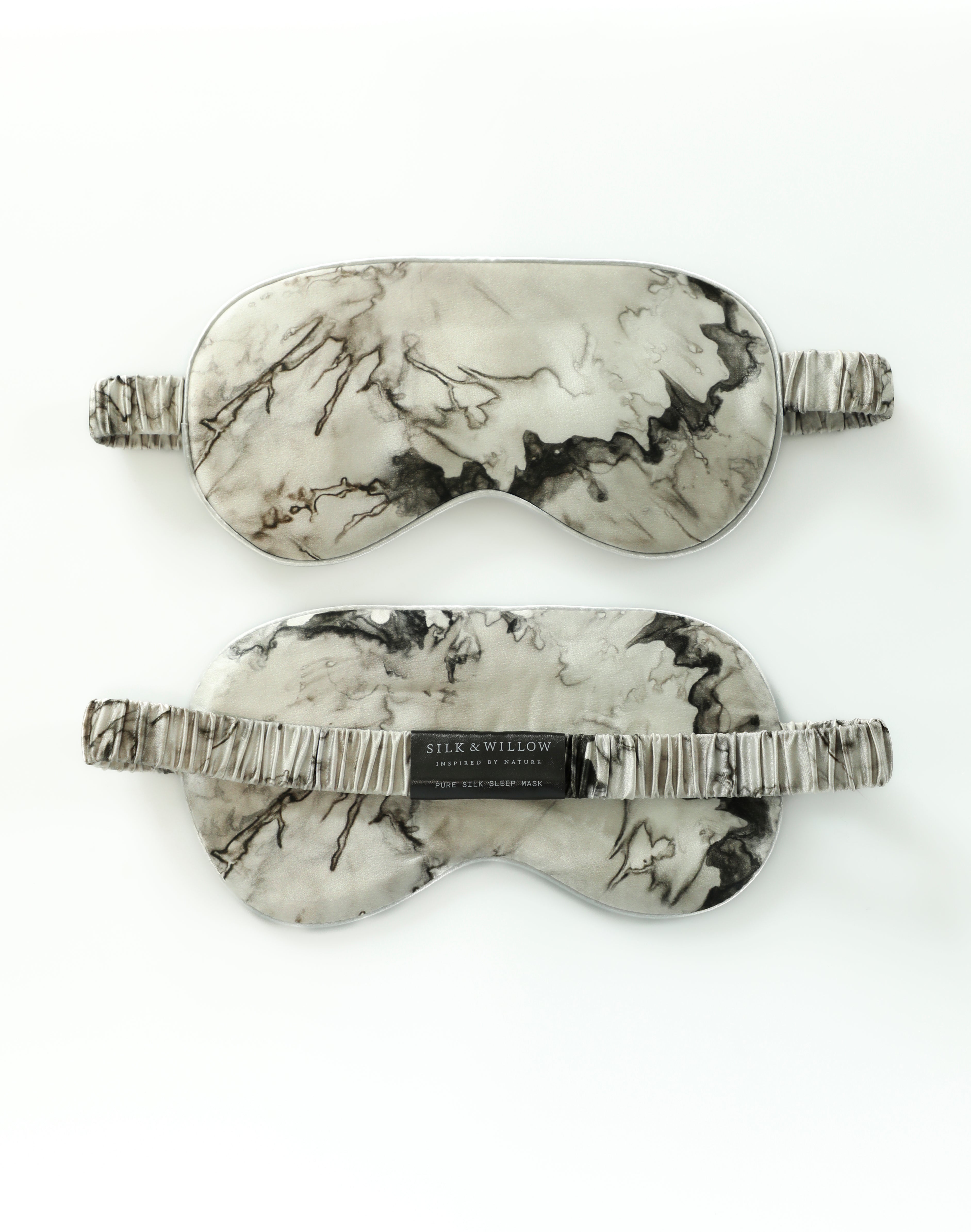 Marble-patterned sleep mask with branded tag on a white background