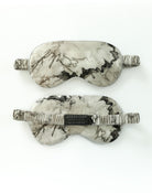 Marble-patterned sleep mask with branded tag on a white background