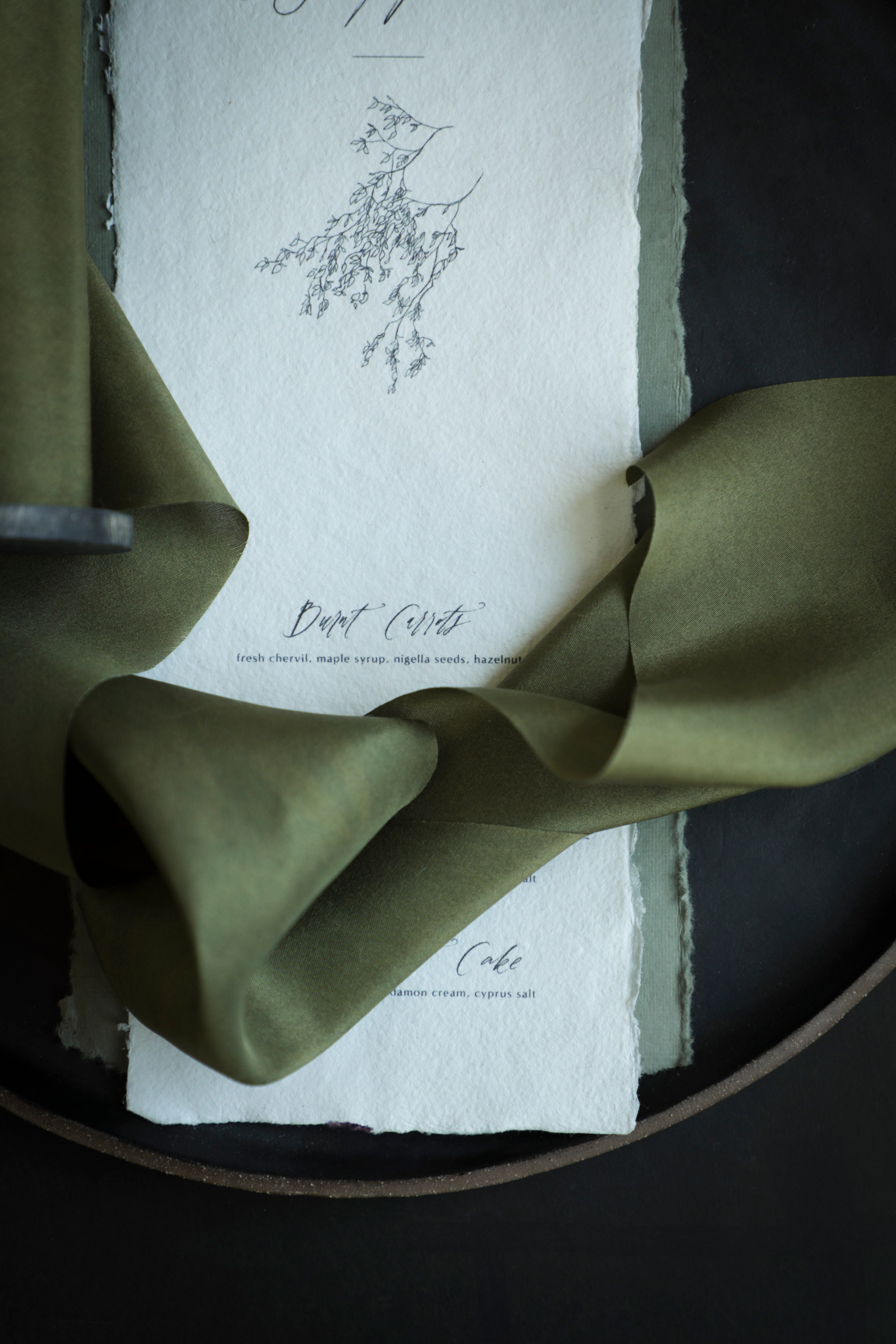 Green ribbon on a white card with text and floral design