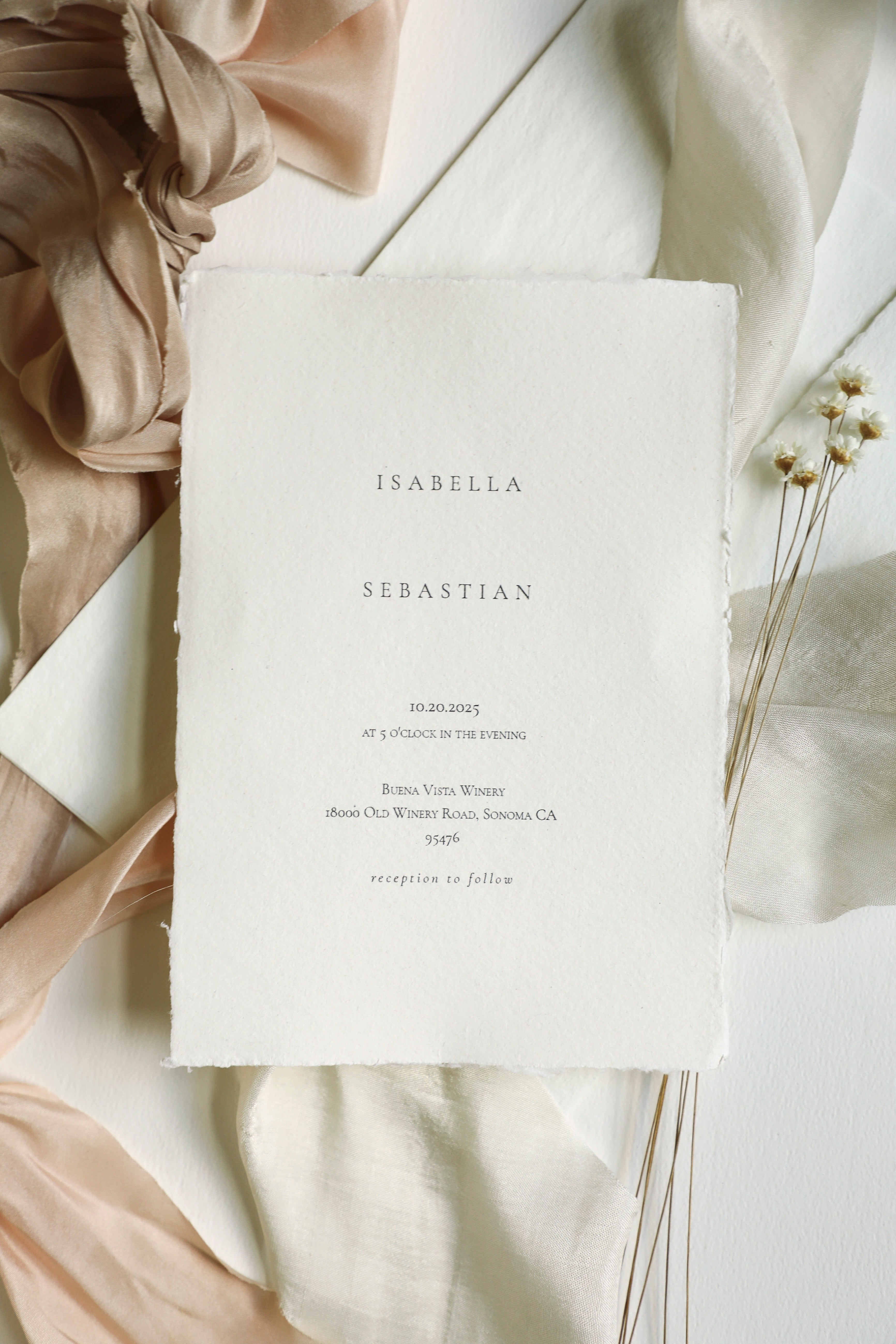 White invitation card with text on a soft beige fabric background