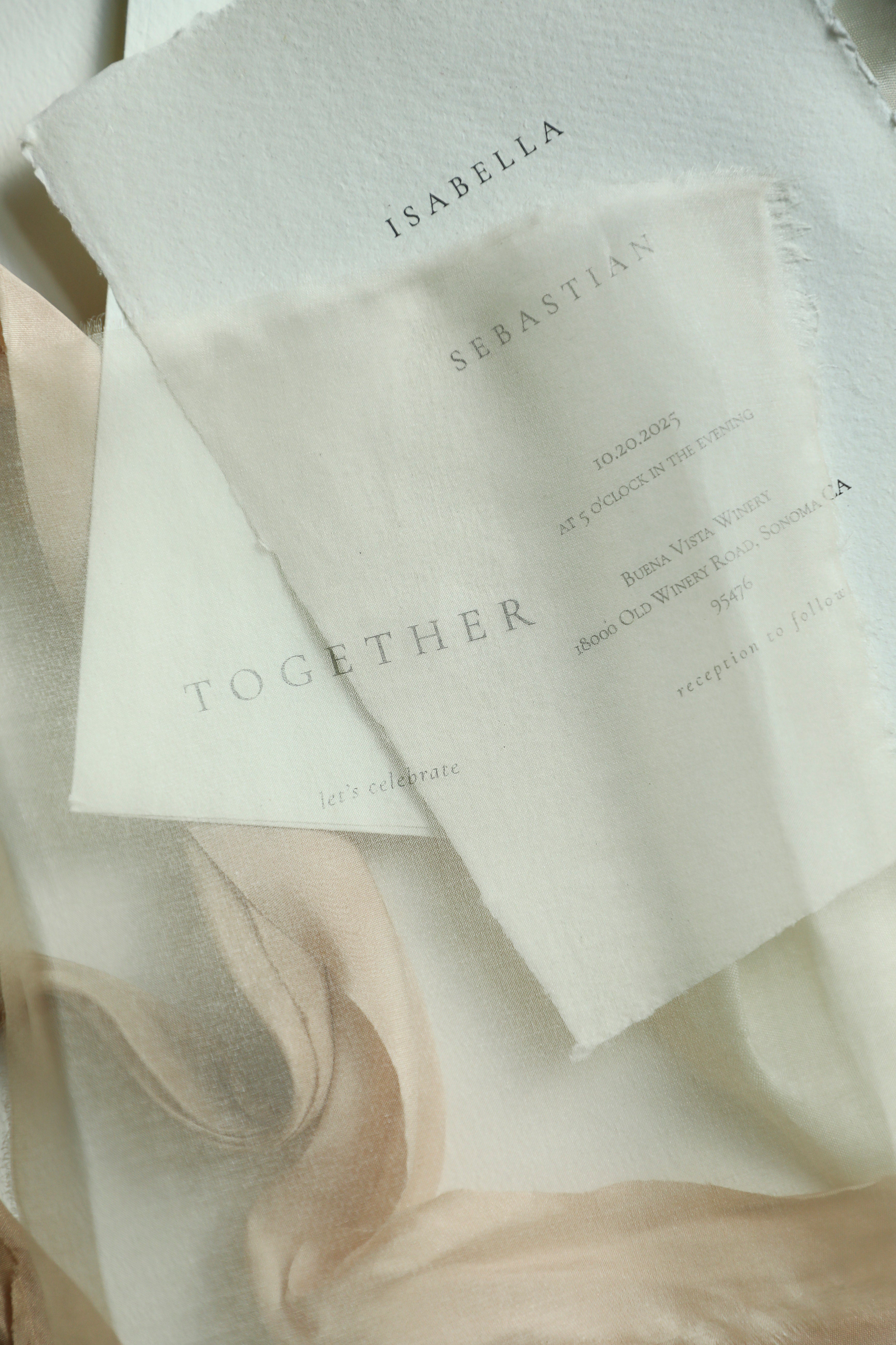 Two white cards with names printed on them, placed on a textured fabric background.