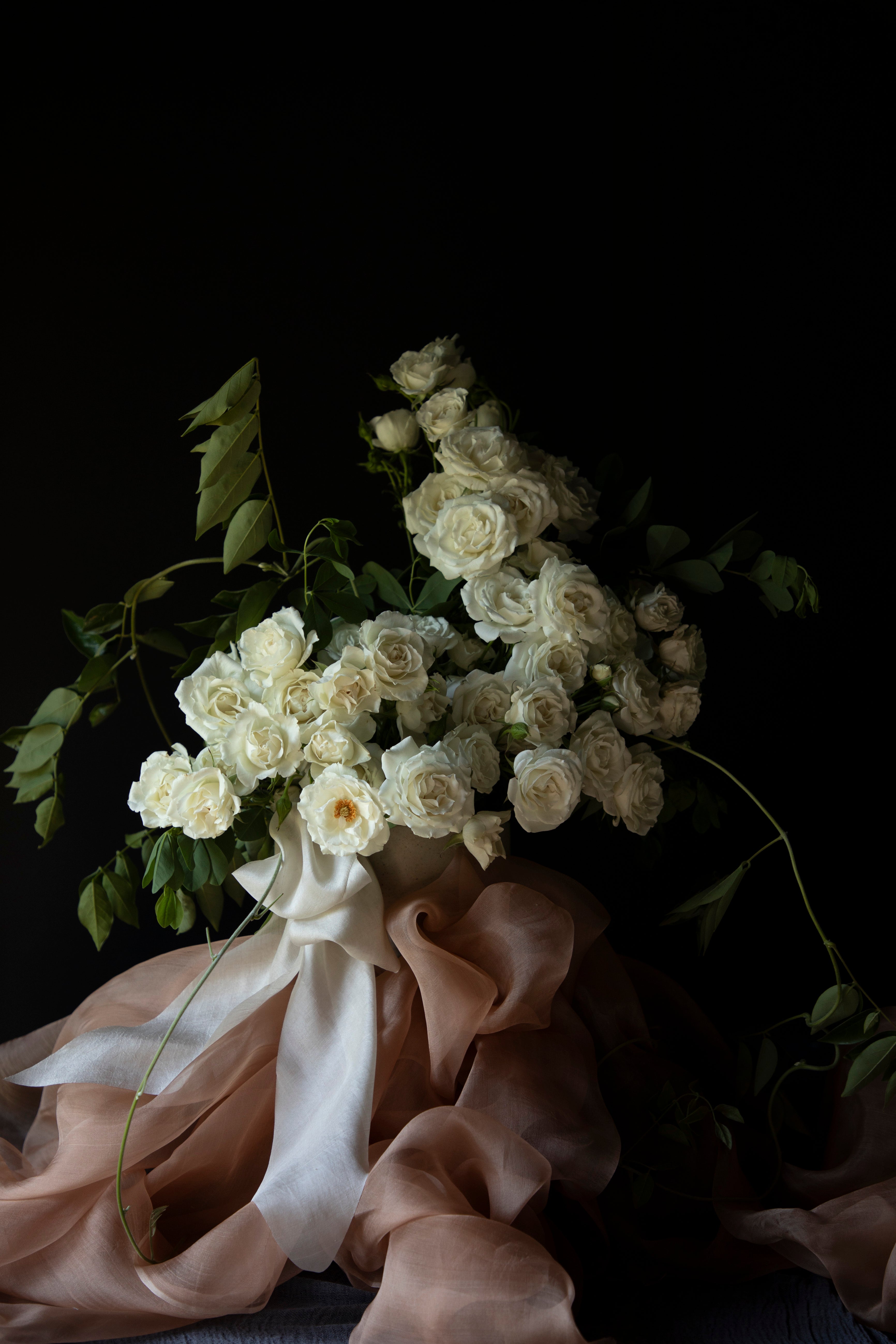 white roses in a floral centerpiece with silk tabletop textiles and ribbons as decor