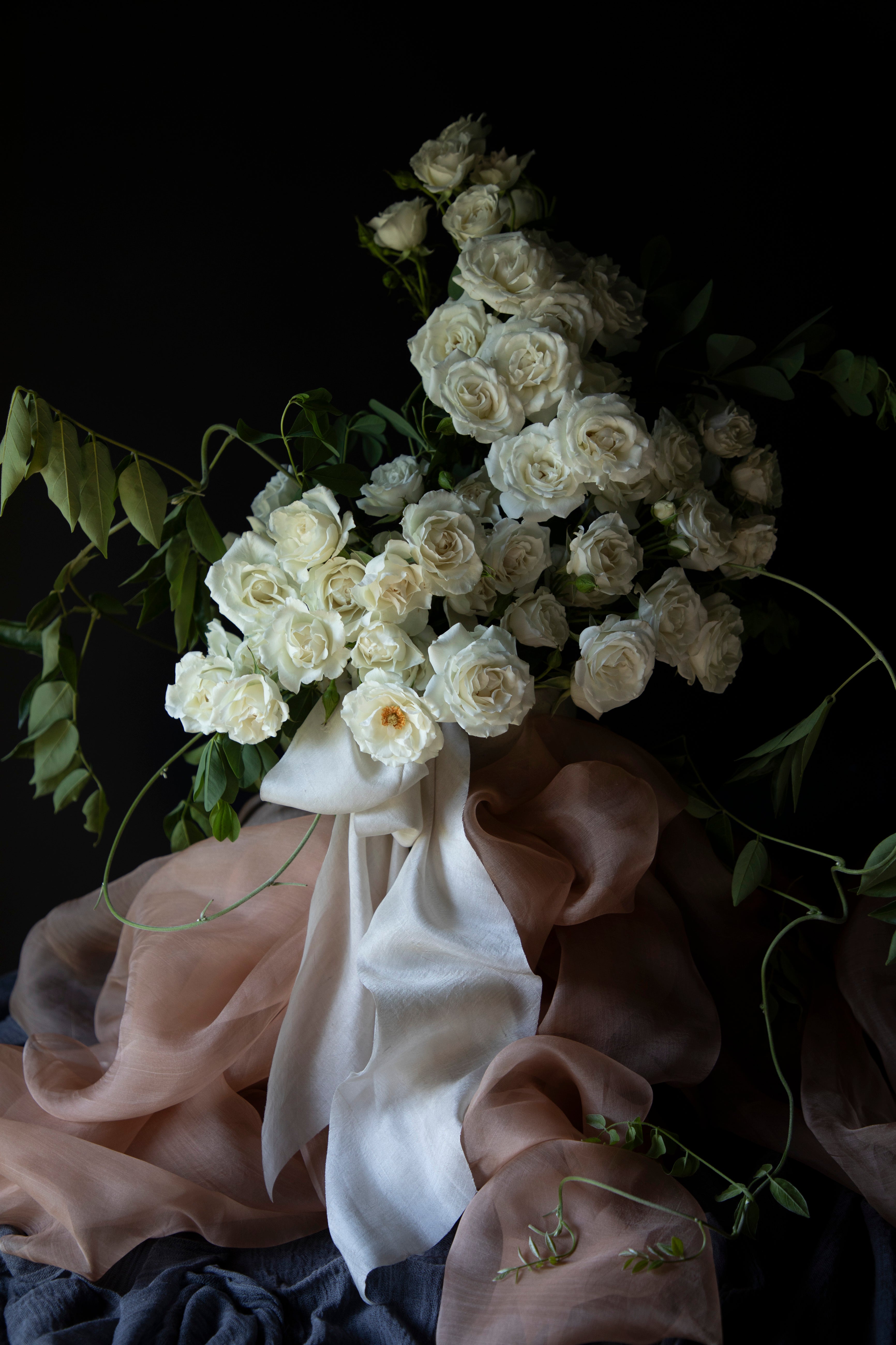 white organic silk ribbon tied on a white rose arrangement for wedding flowers 