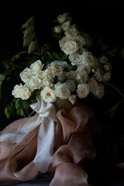 white rose floral centerpiece with peach accent and decorated with organic silk ribbon