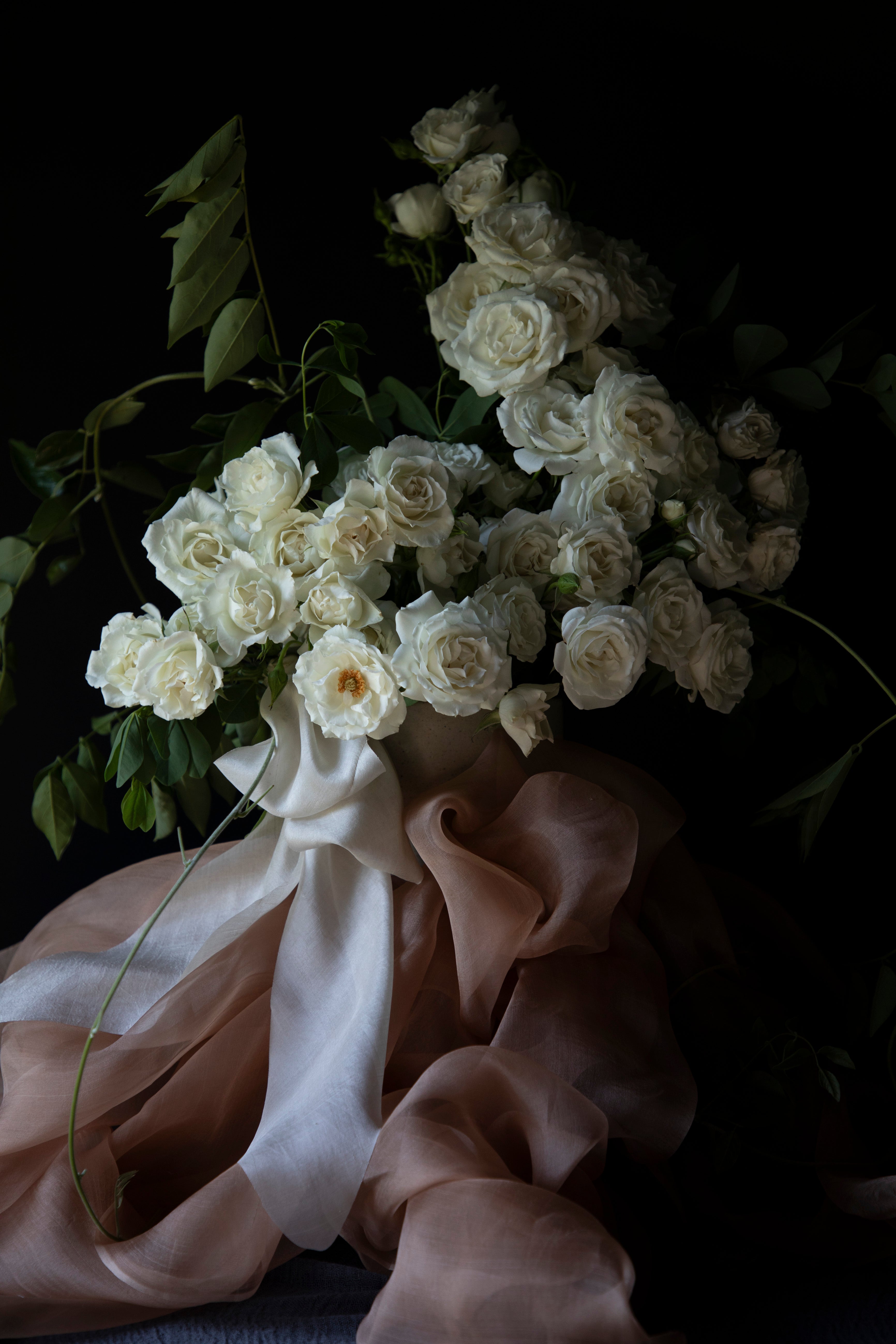 white rose floral centerpiece with peach accent and decorated with organic silk ribbon