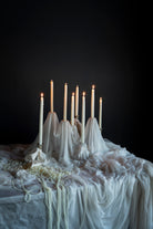 Candle holder with lit candles on a draped surface against a dark background