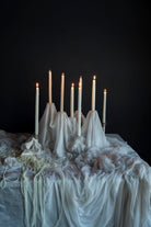 Candelabrum with lit candles on a draped tablecloth against a dark background