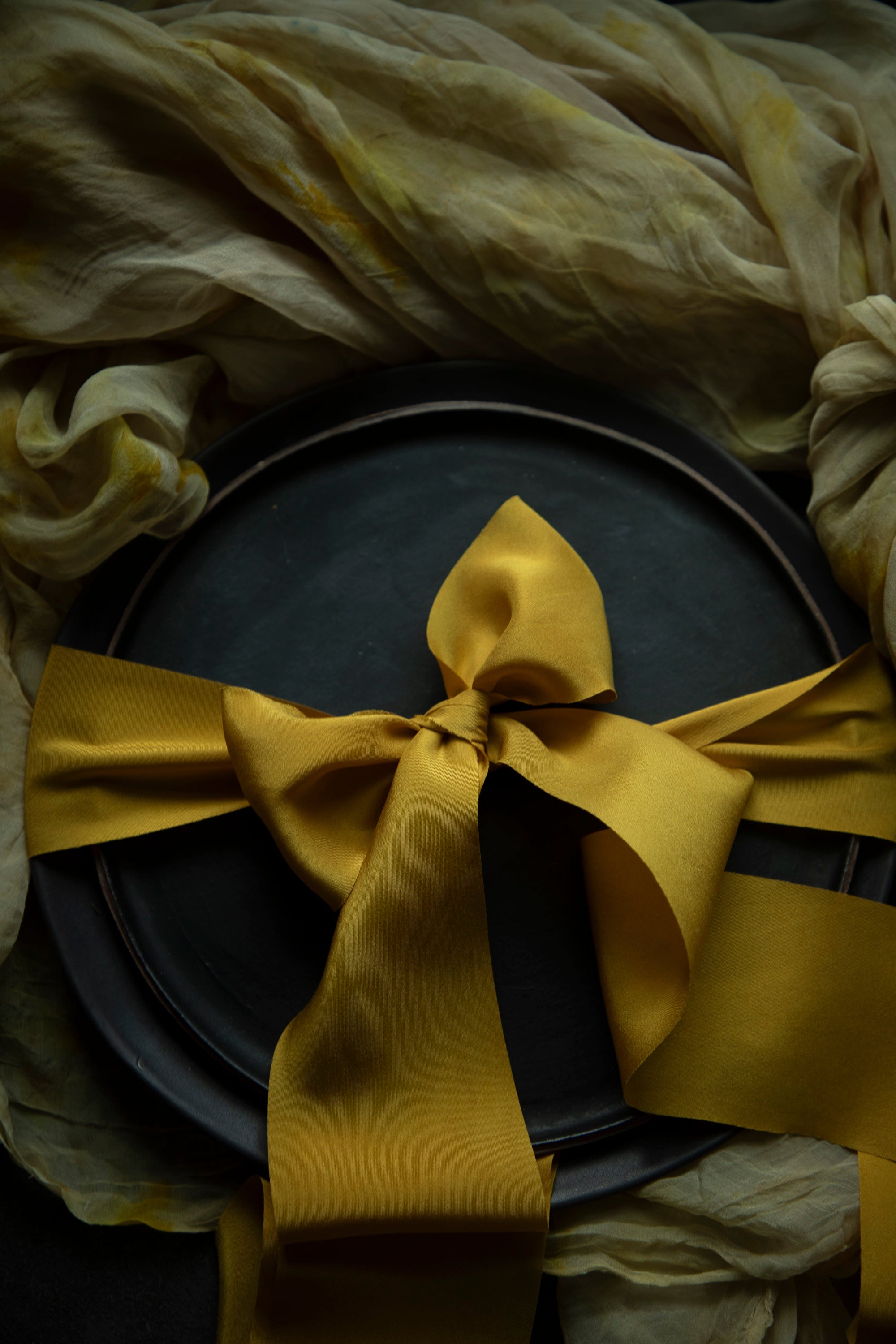 A luxurious plant-dyed silk ribbon in a rich gold hue, elegantly draped, showcasing its soft texture and delicate sheen. Ideal for wrapping bridal bouquets, this ribbon is perfect for brides-to-be, engaged couples, and florists looking to add a touch of sophistication to wedding arrangements.