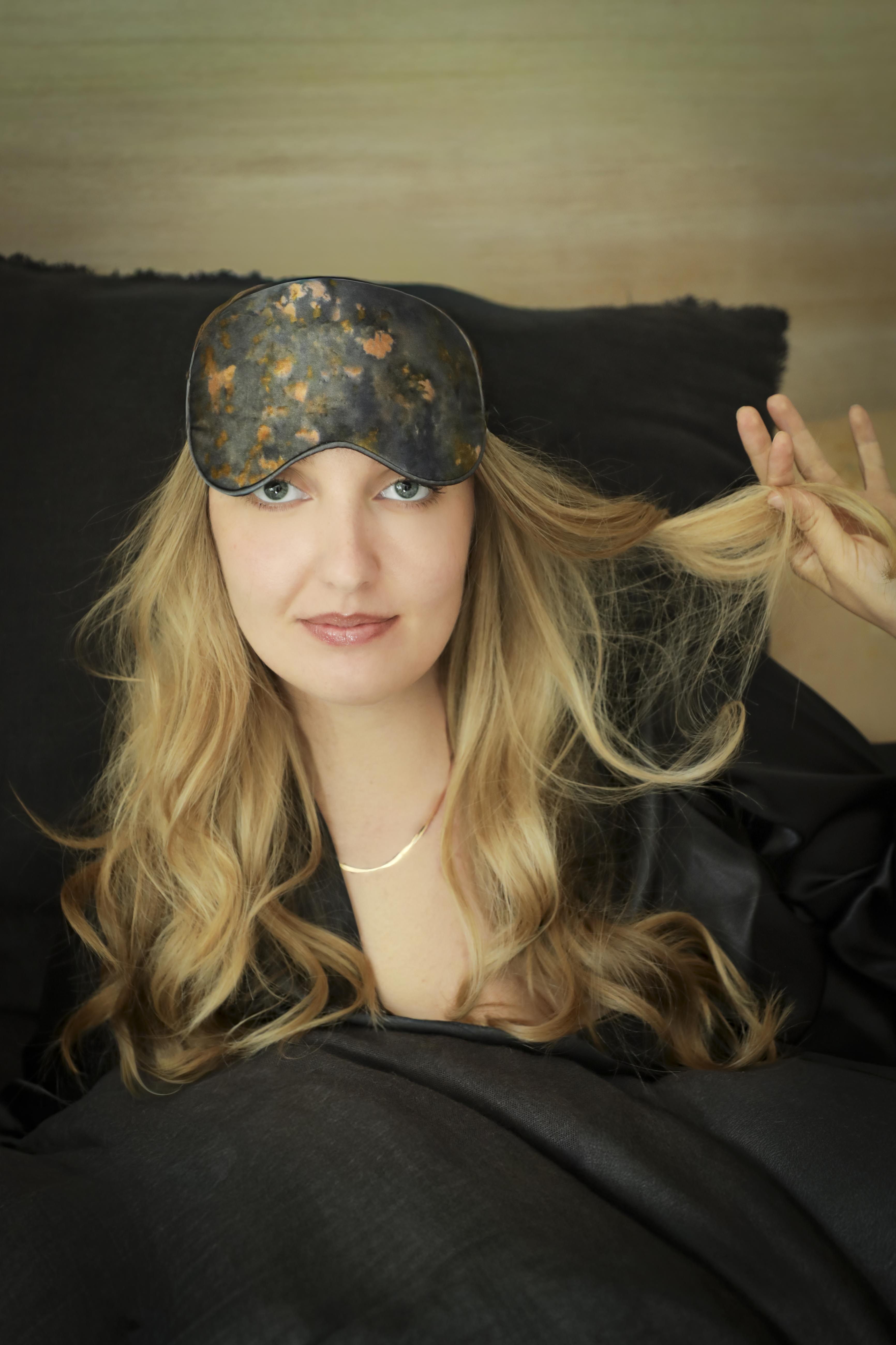 Woman wearing a decorative silk sleep mask with a blurred background