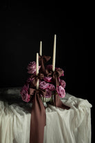 Decorative floral arrangement with candles on a Wedding tablescape with white draping textiles featuring Silk & Willow Chocolate Rose silk ribbons.