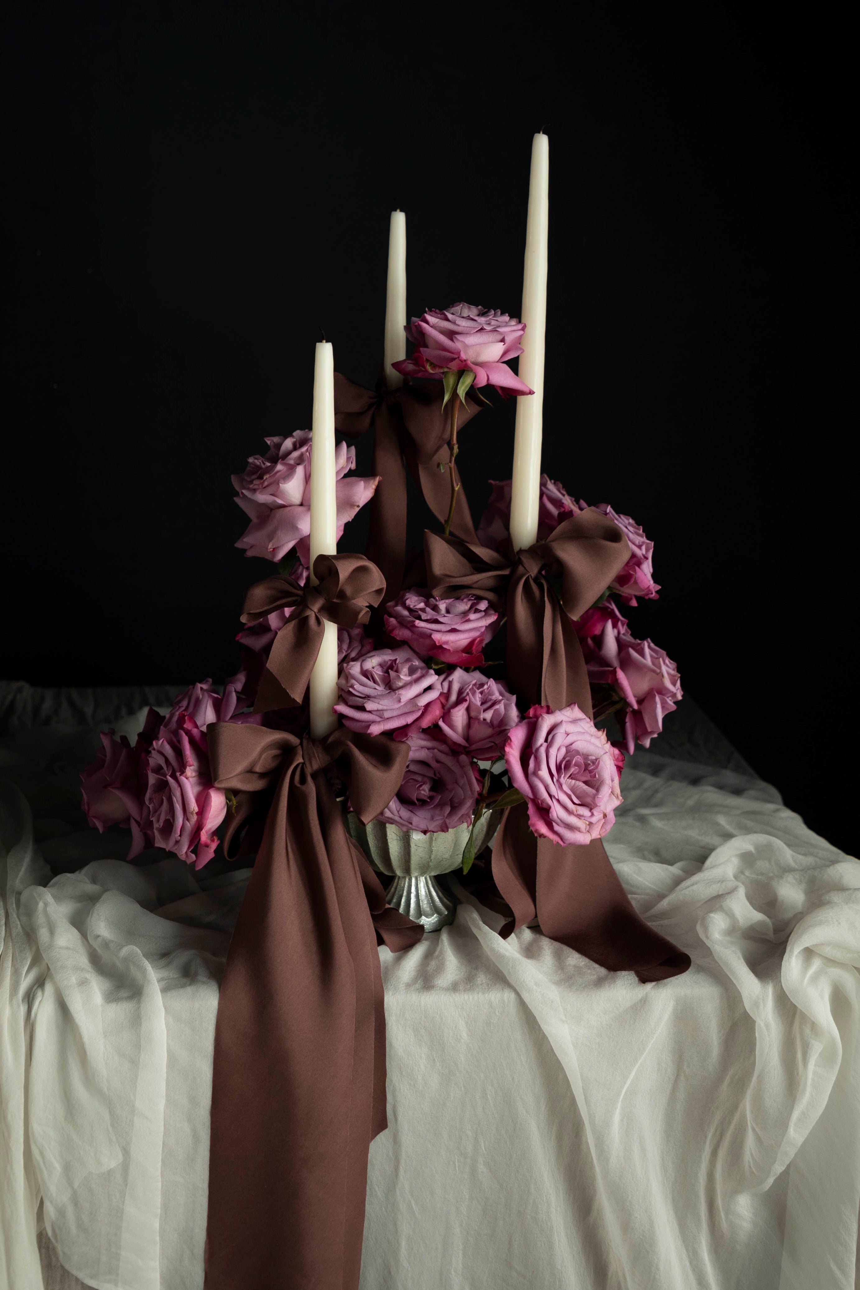 Decorative floral arrangement with candles on a dark background