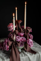 Decorative floral arrangement with candles on a tablecloth against a dark background. Featuring Silk & Willow Chocolate Rose silk ribbons.