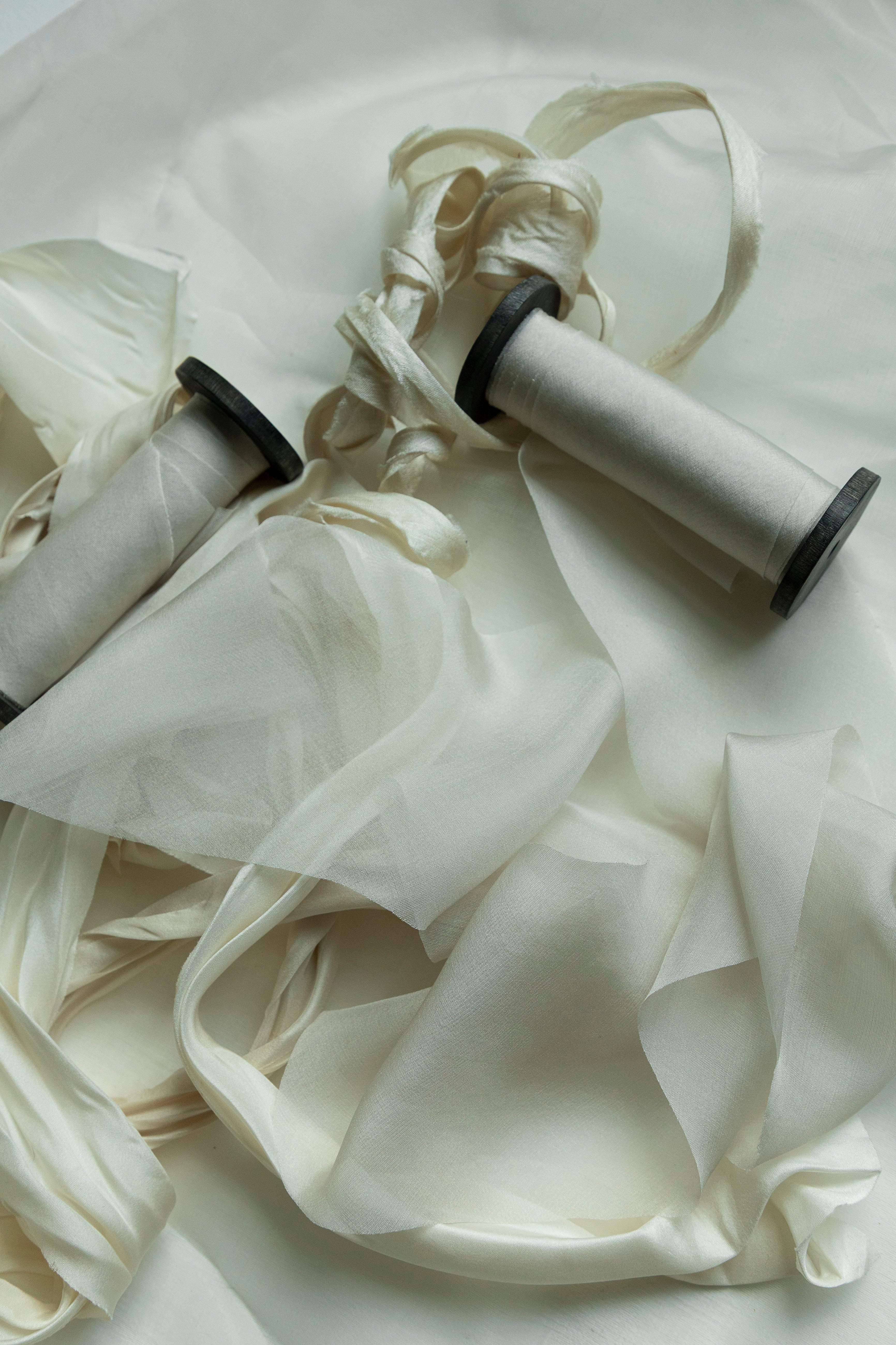 Two spools of dove silk ribbon on black vintage spool on a white background