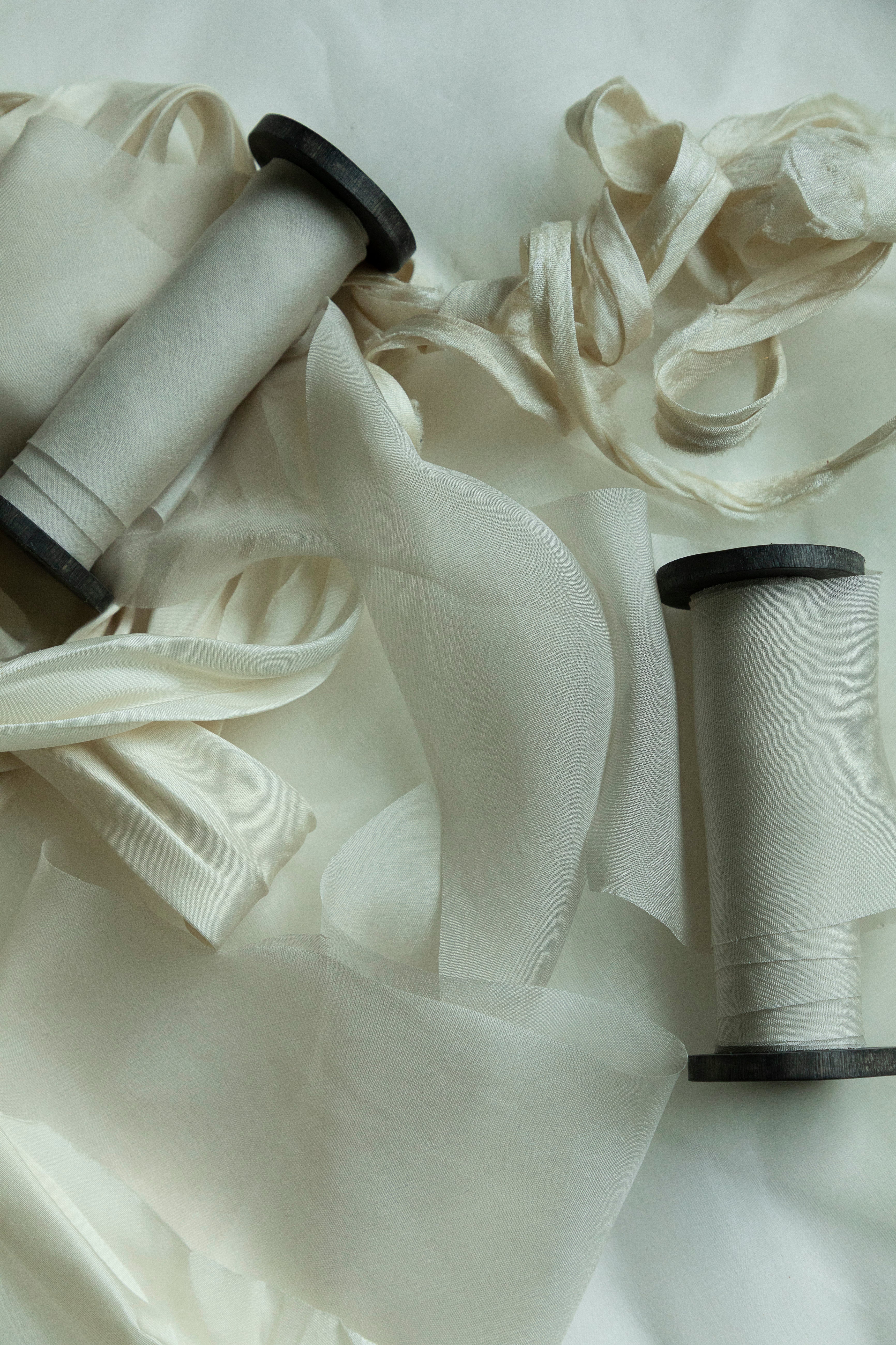 Two spools of white ribbon on a light background