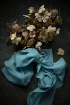 Bouquet of dried flowers with a blue ribbon on a dark surface