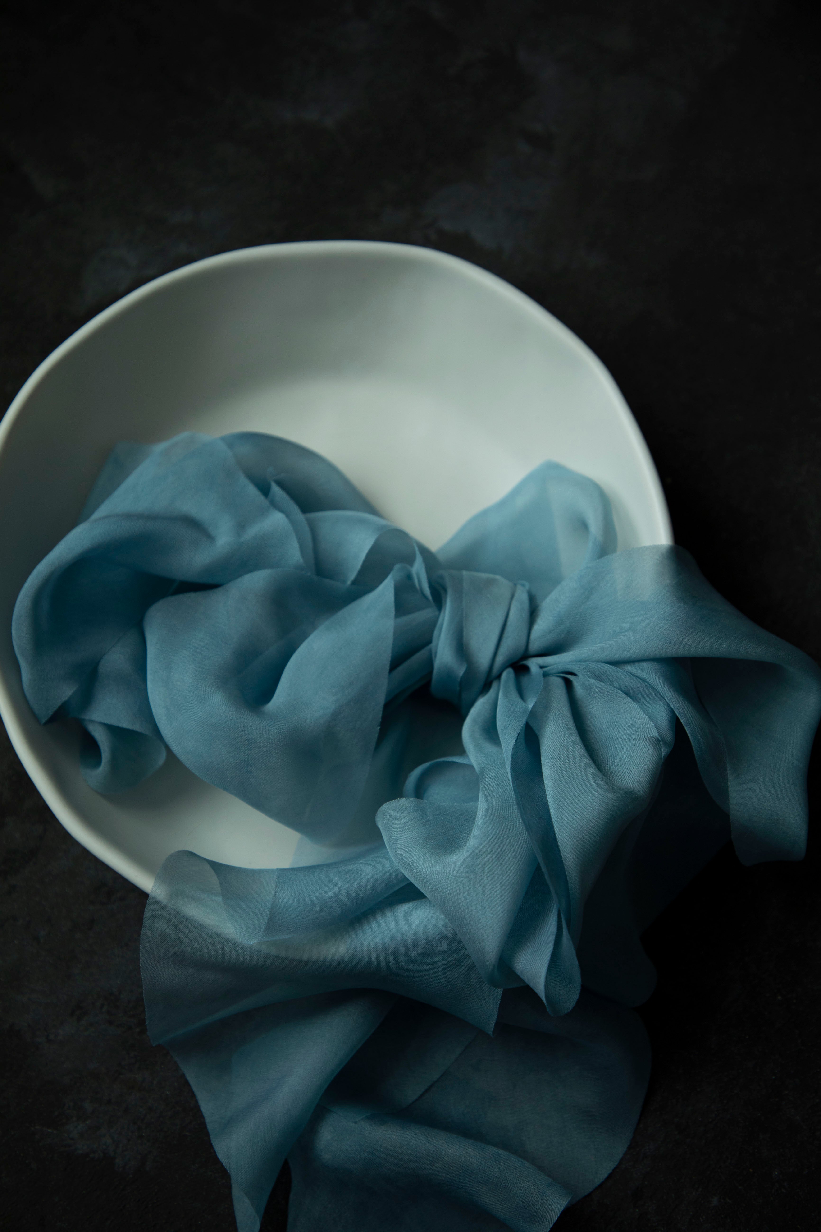 Duchess Blue silk ribbons on a white plate against a dark background