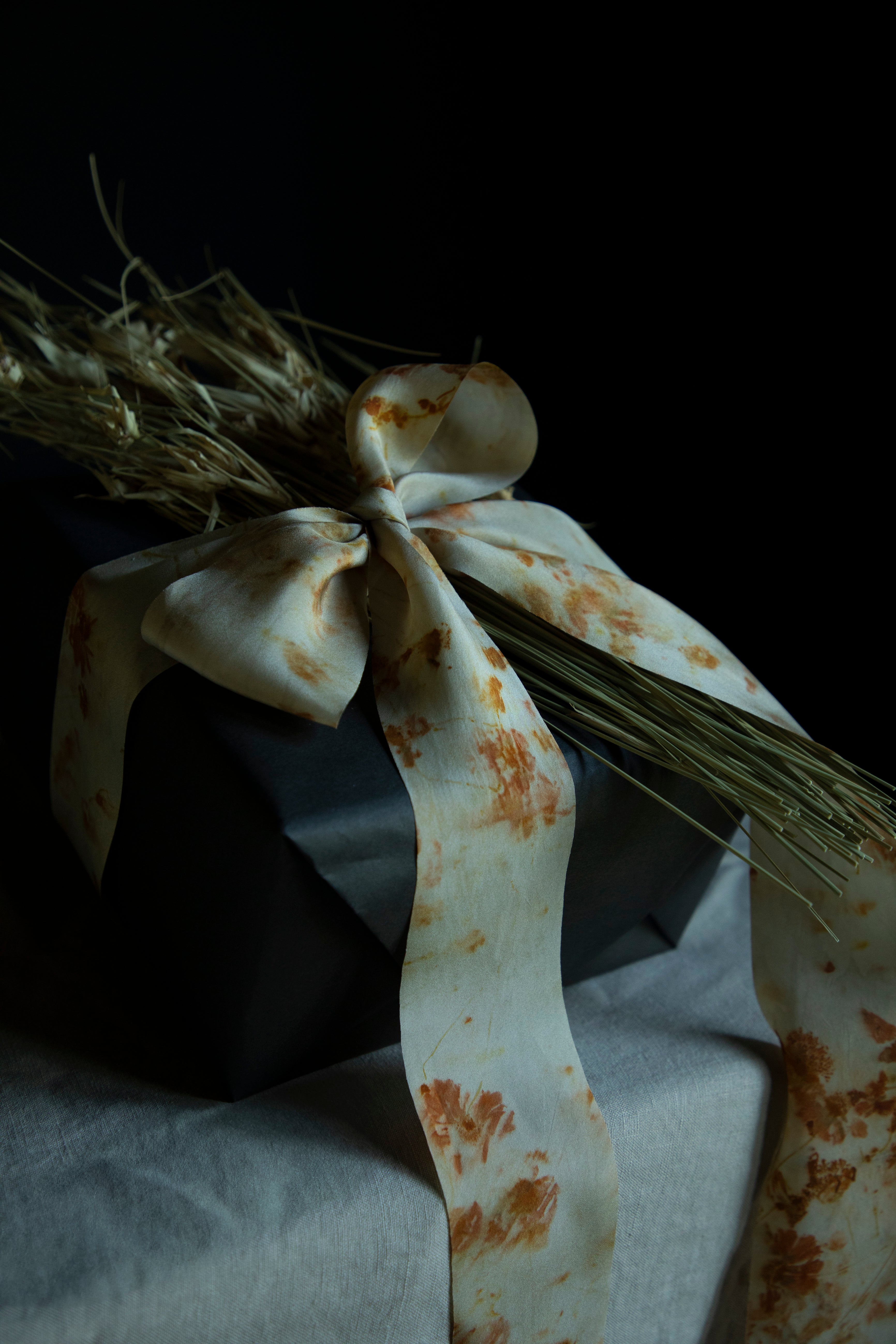 Gift wrapped in brown paper with a decorative ribbon on a dark background