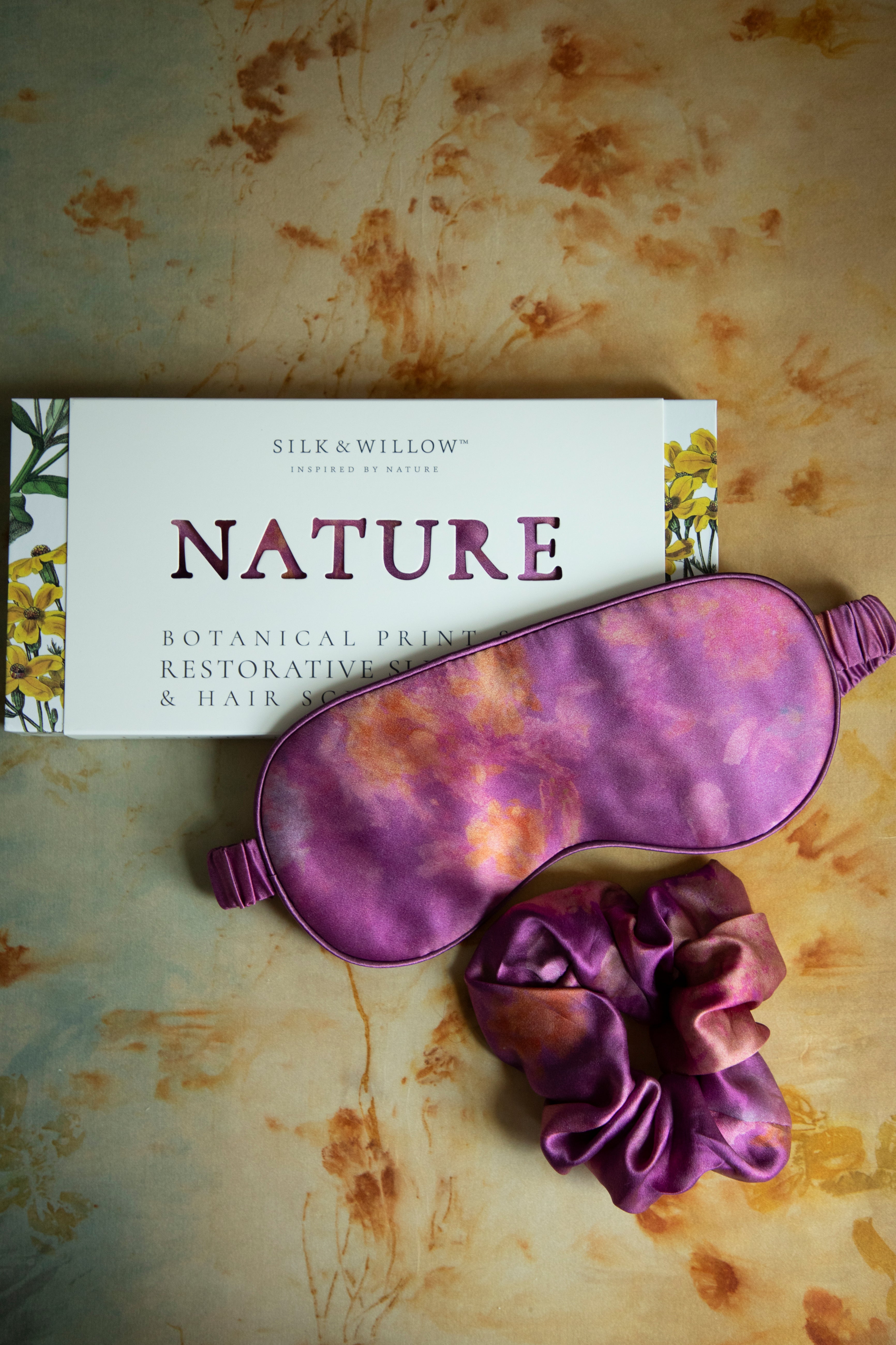 A luxurious silk sleep mask and hair scrunchie set featuring delicate botanical patterns, elegantly displayed in a sustainable gift box, perfect for a sophisticated and eco-conscious touch.