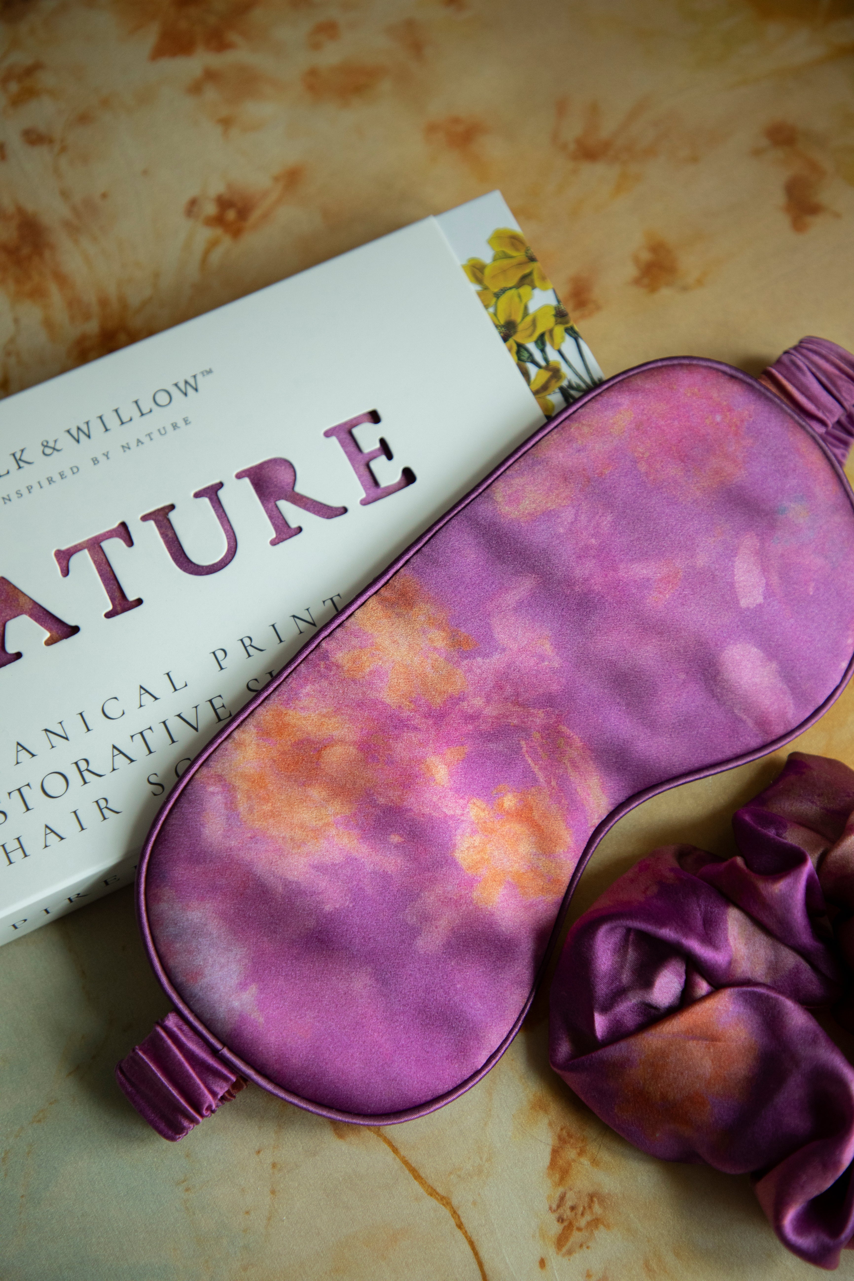 A luxurious silk sleep mask and hair scrunchie set featuring delicate botanical patterns, elegantly displayed in a sustainable gift box, perfect for a sophisticated and eco-conscious touch.