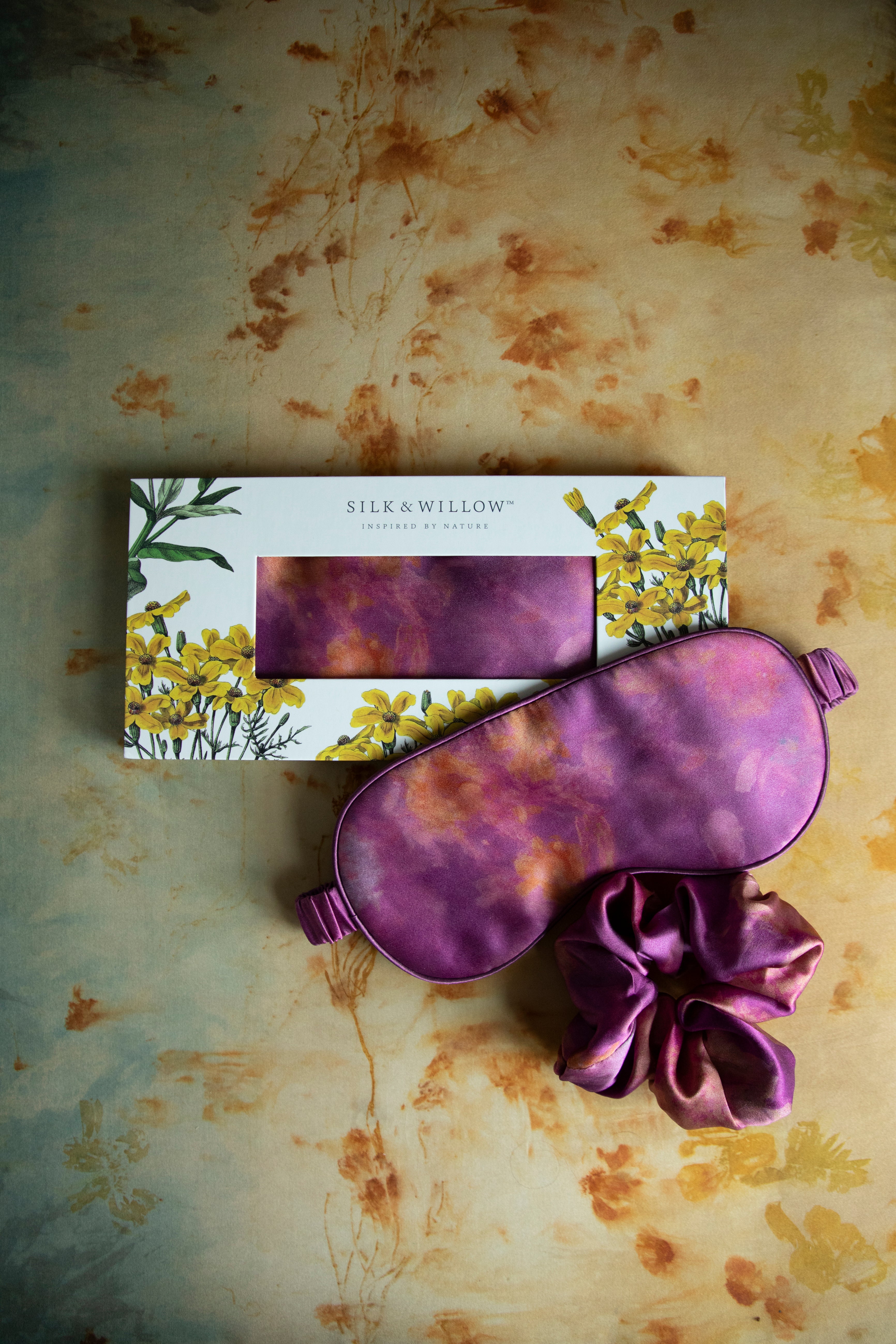 A luxurious silk sleep mask and hair scrunchie set featuring delicate botanical patterns, elegantly displayed in a sustainable gift box, perfect for a sophisticated and eco-conscious touch.
