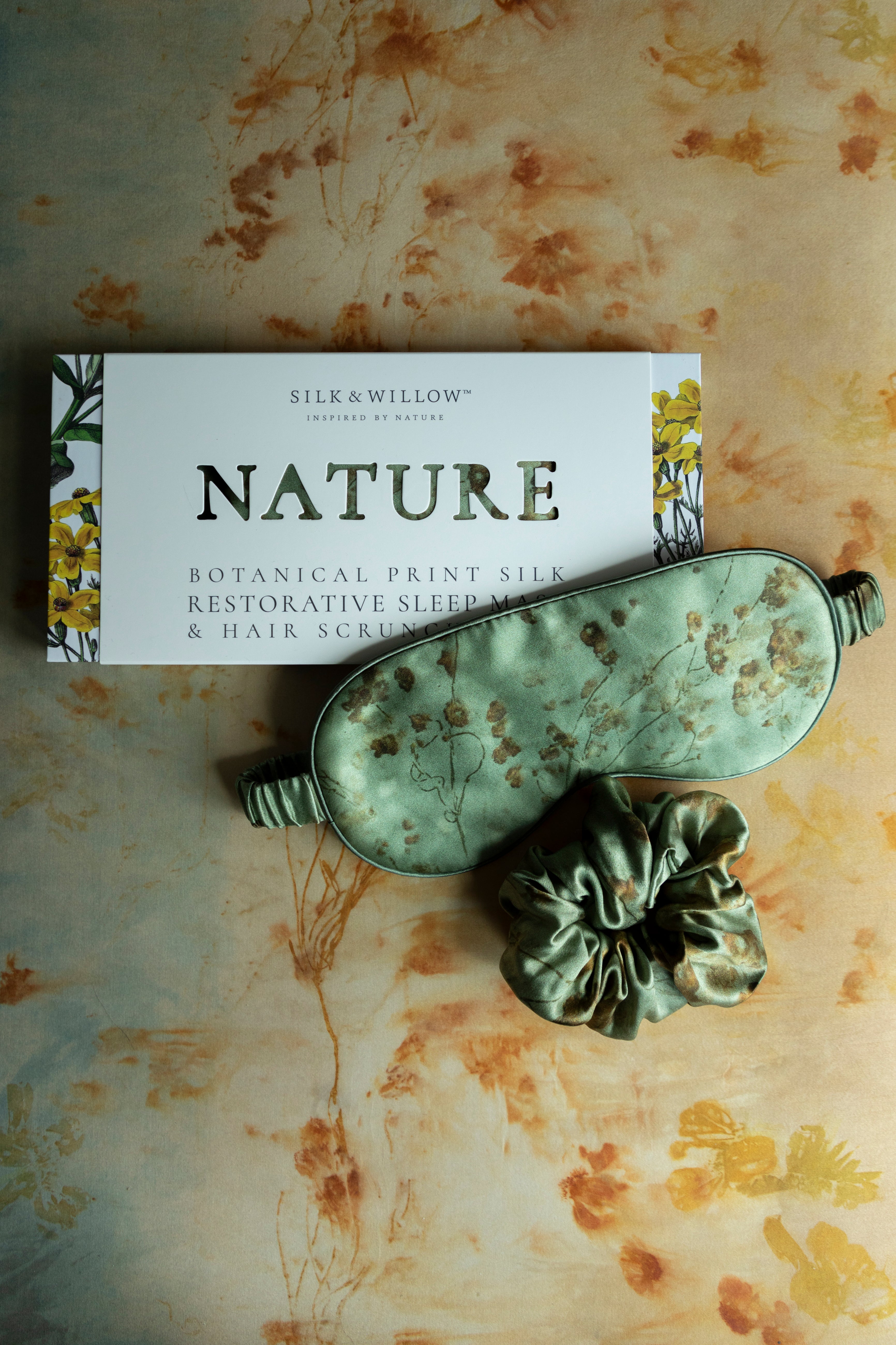 luxury silk sleep eye mask placed next to gift packaging with "nature" dye cut.