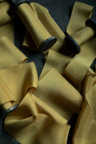Close-up of yellow ribbon on spools against a dark background