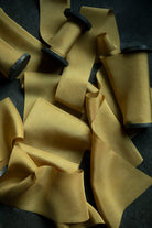 Yellow hand dyed silk ribbon on a dark surface