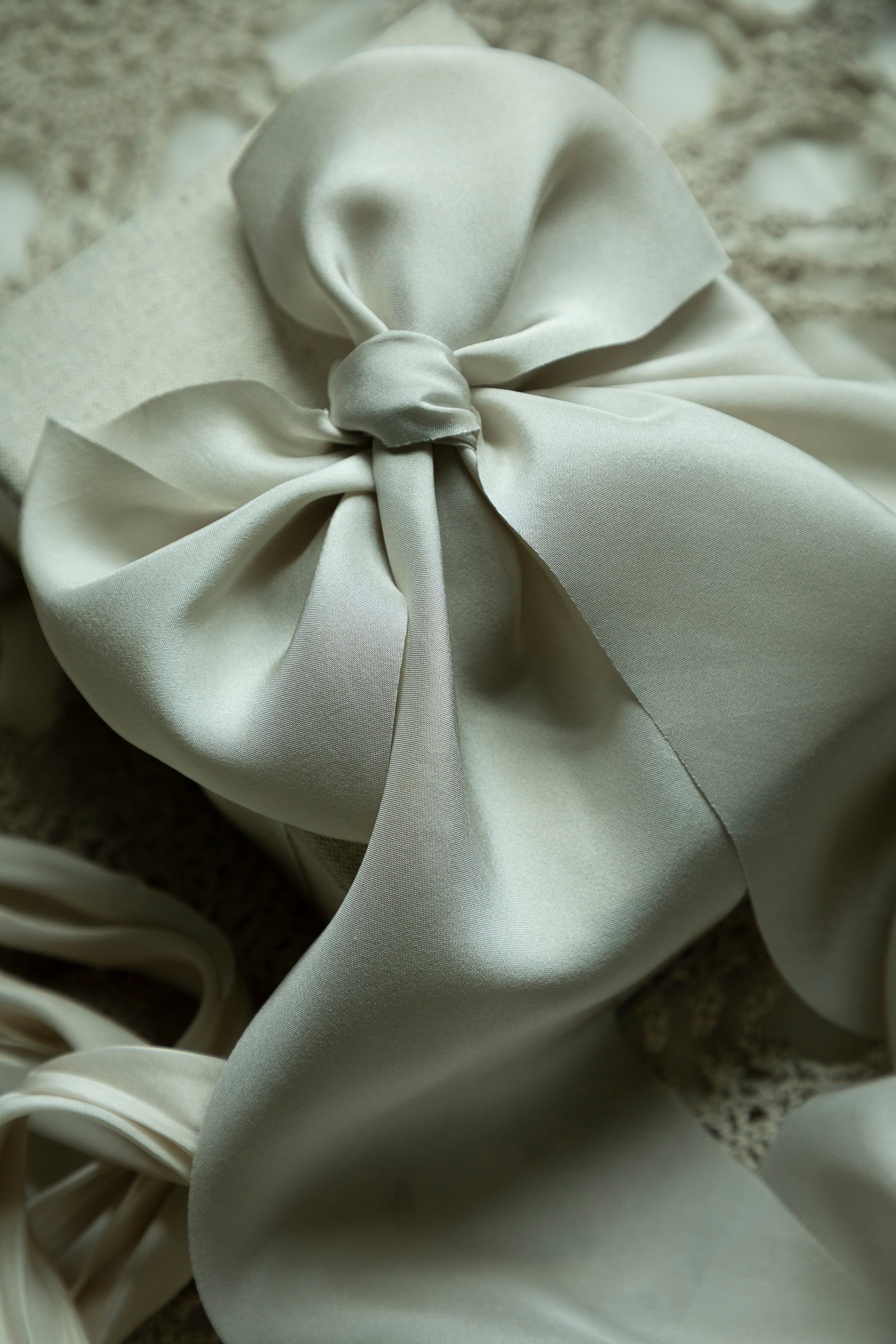 Close-up of a light gray fabric bow on a textured surface