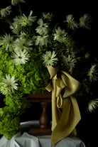 Floral arrangement with greenery and a citrus yellow ribbon on a dark background