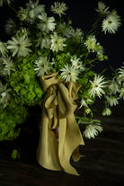 Bouquet of green and white flowers with a Chartreuse yellow ribbon on a dark background
