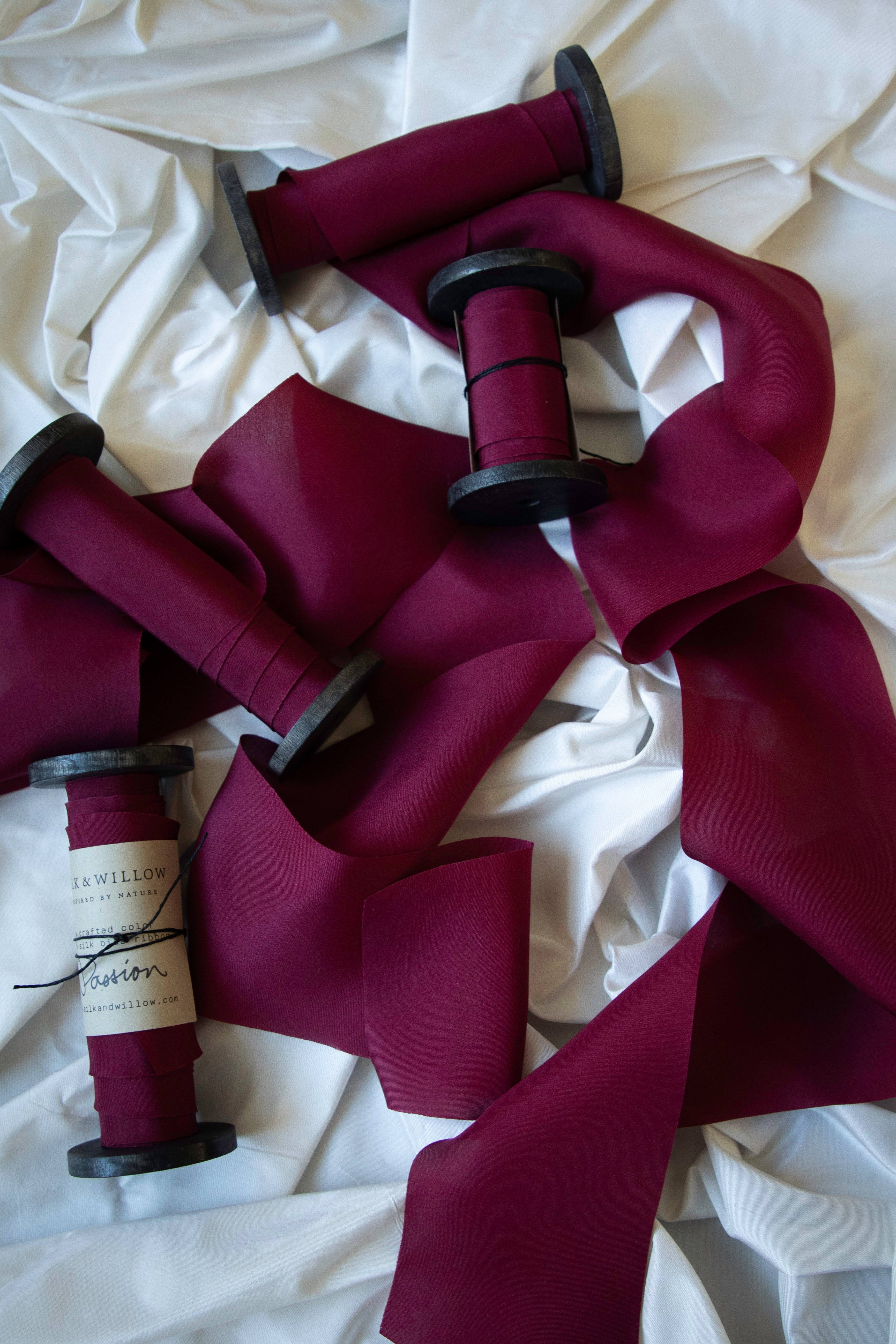 Passion red silk ribbon on wood spools on a white background.